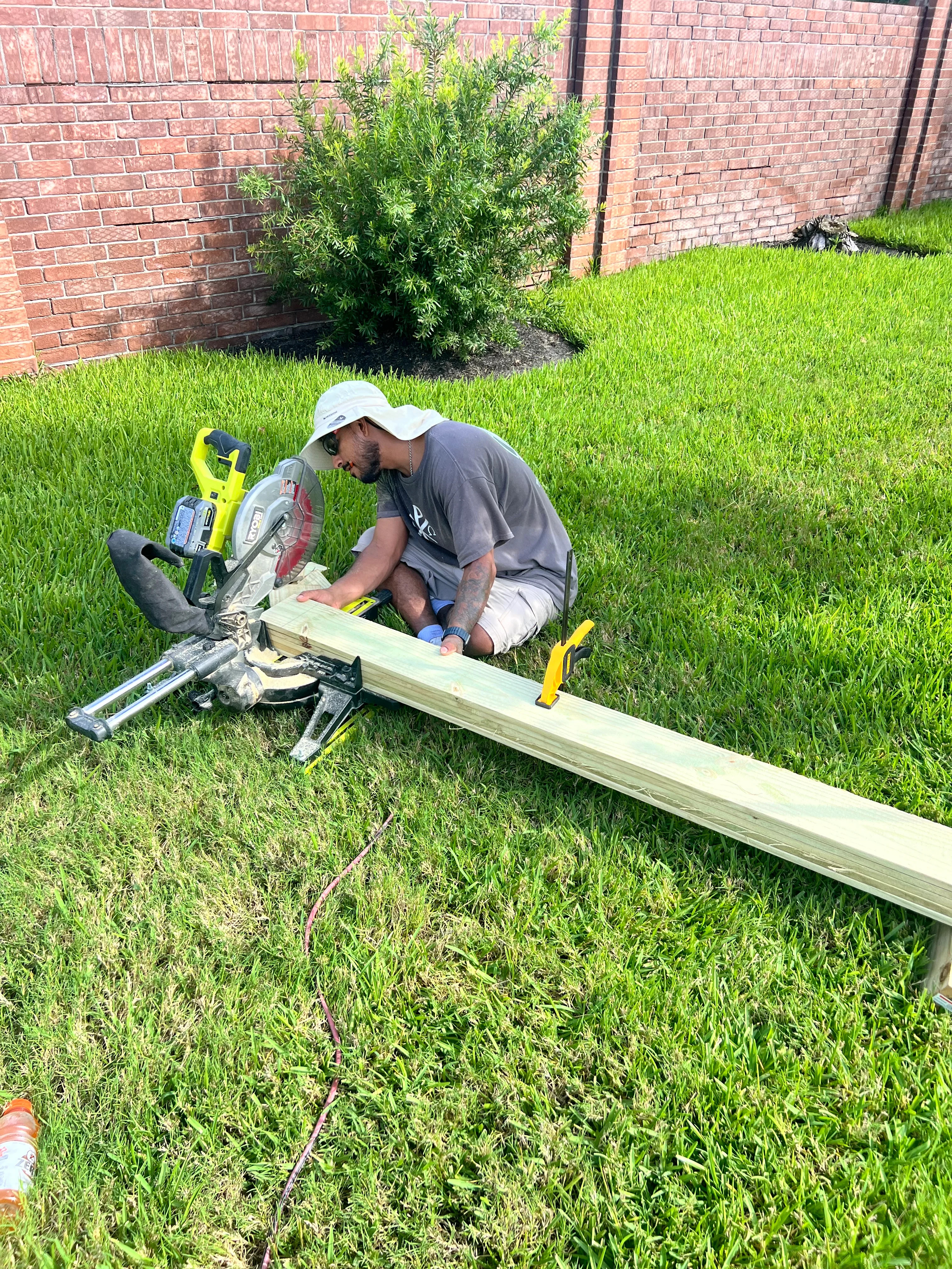 Contractor cutting and assembling pressure-treated deck framing in backyard