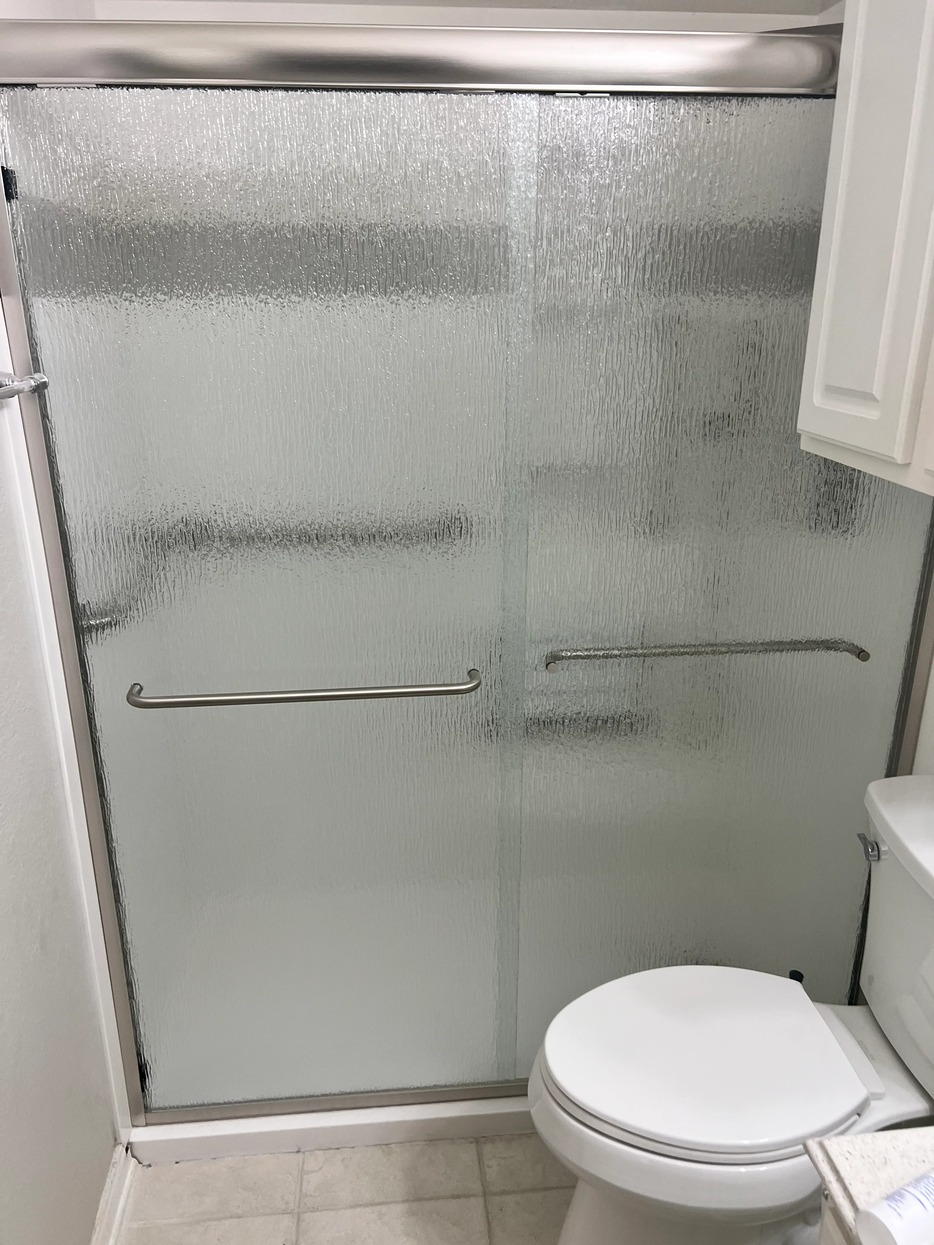 Frameless glass shower enclosure with textured panels and brushed nickel sliding doors