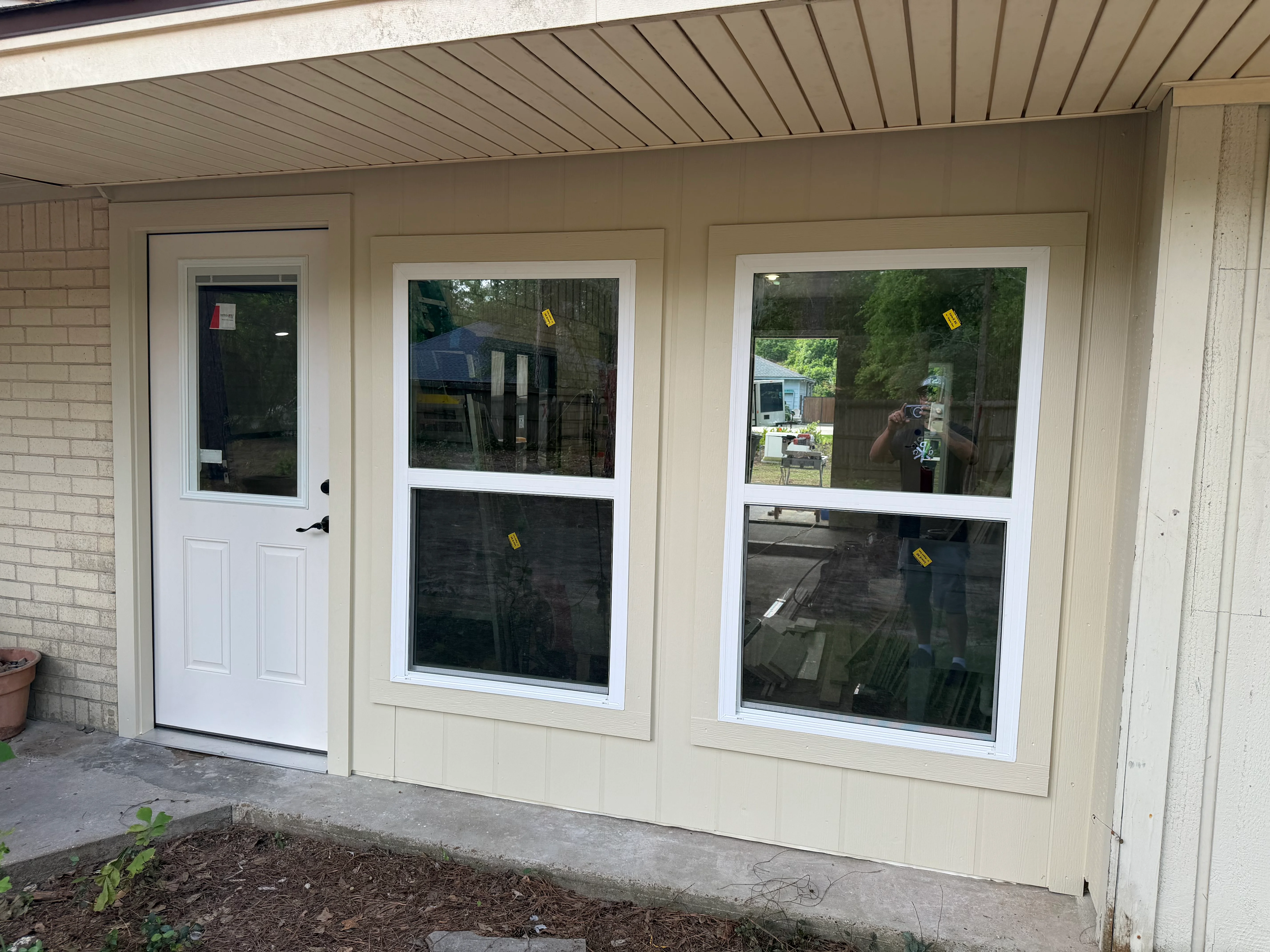 White-framed storefront windows and entry door installed on cream exterior with metal roof overhang