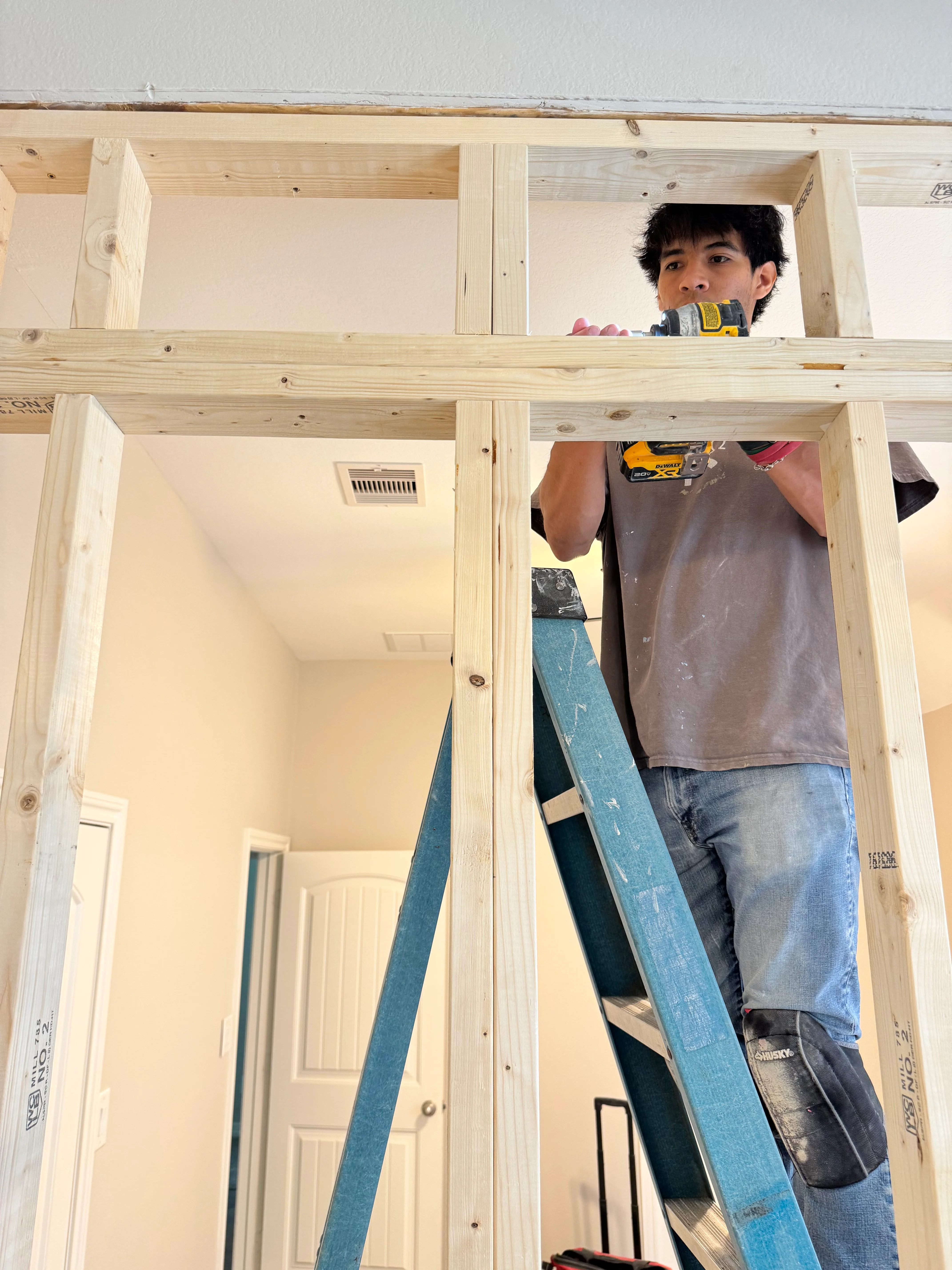 Worker installing drywall on newly framed interior walls during home remodeling project