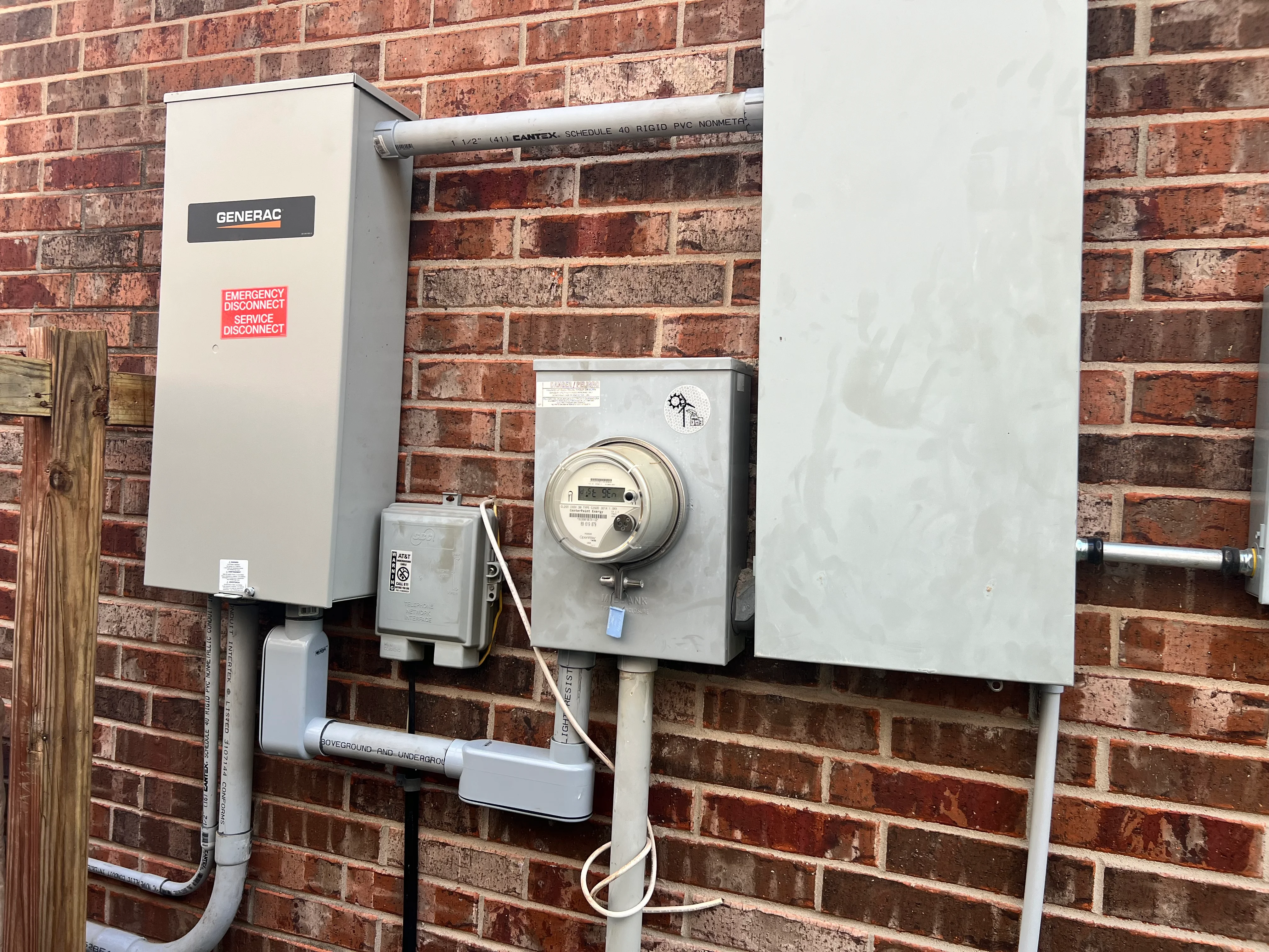 Generac generator with electrical panel and meter installed on brick home exterior