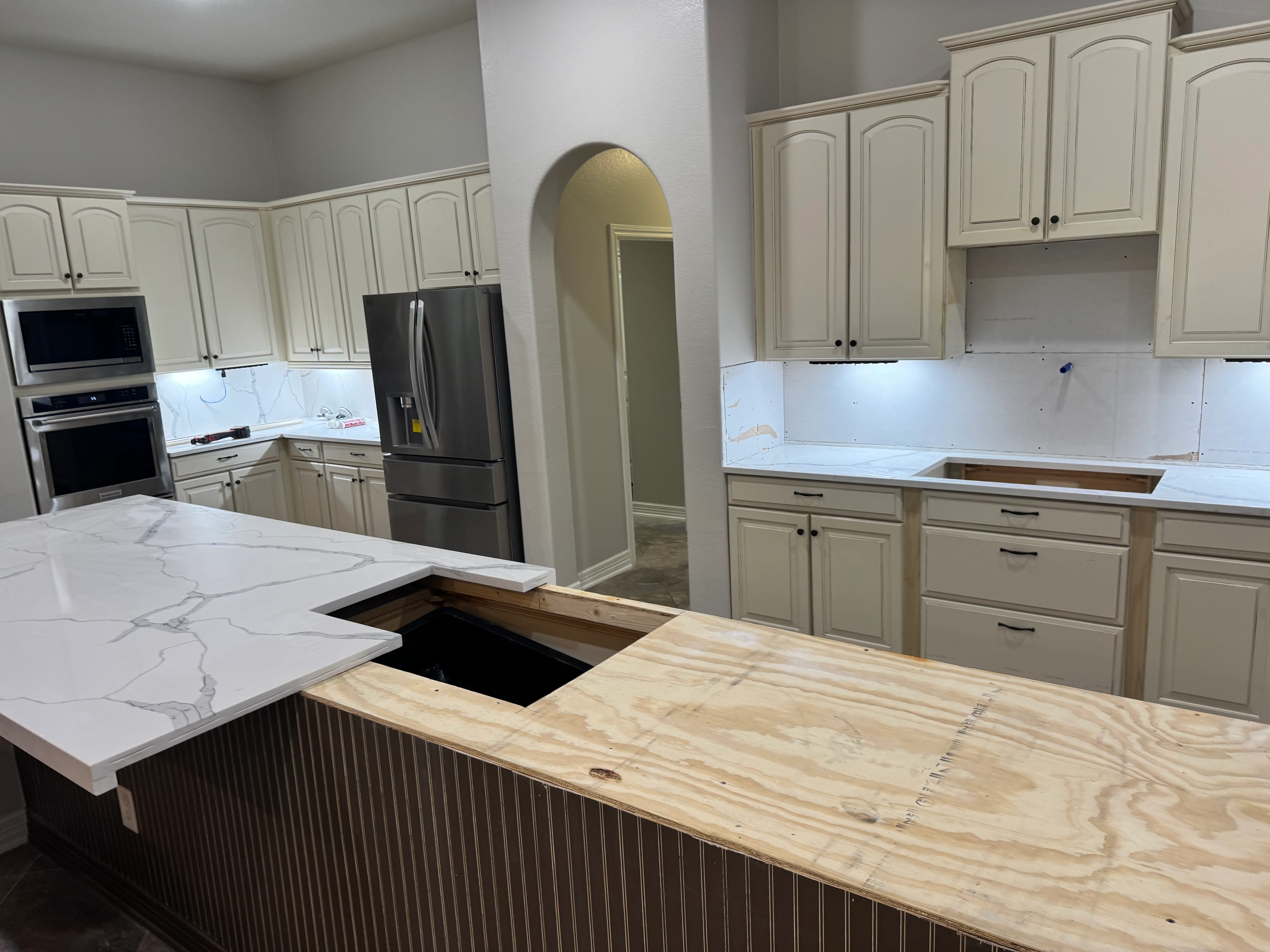 Kitchen remodel with cream cabinets, quartz countertops, stainless steel appliances, and wood island