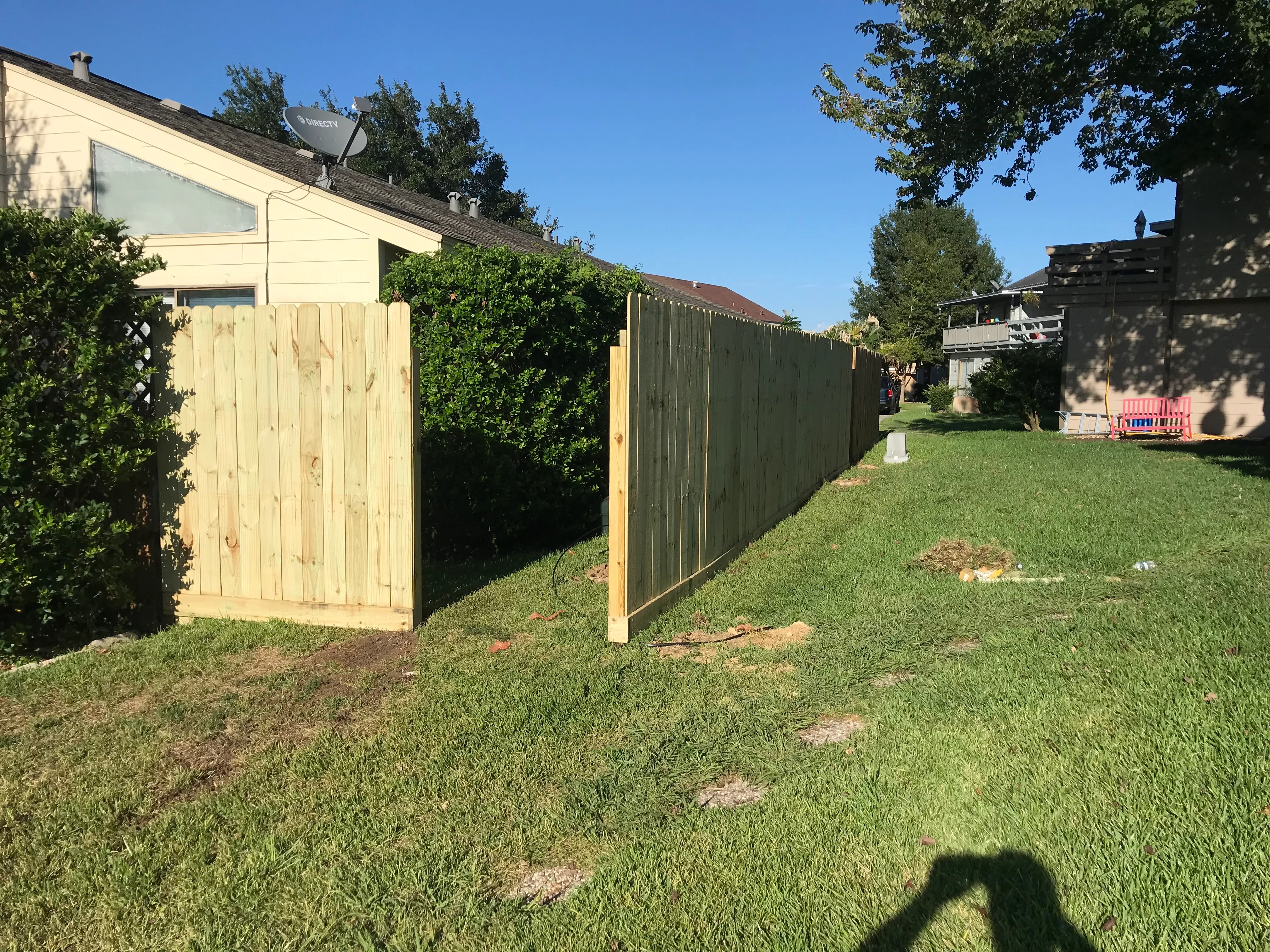 Backyard fence installation with natural wood gate and green metal panels