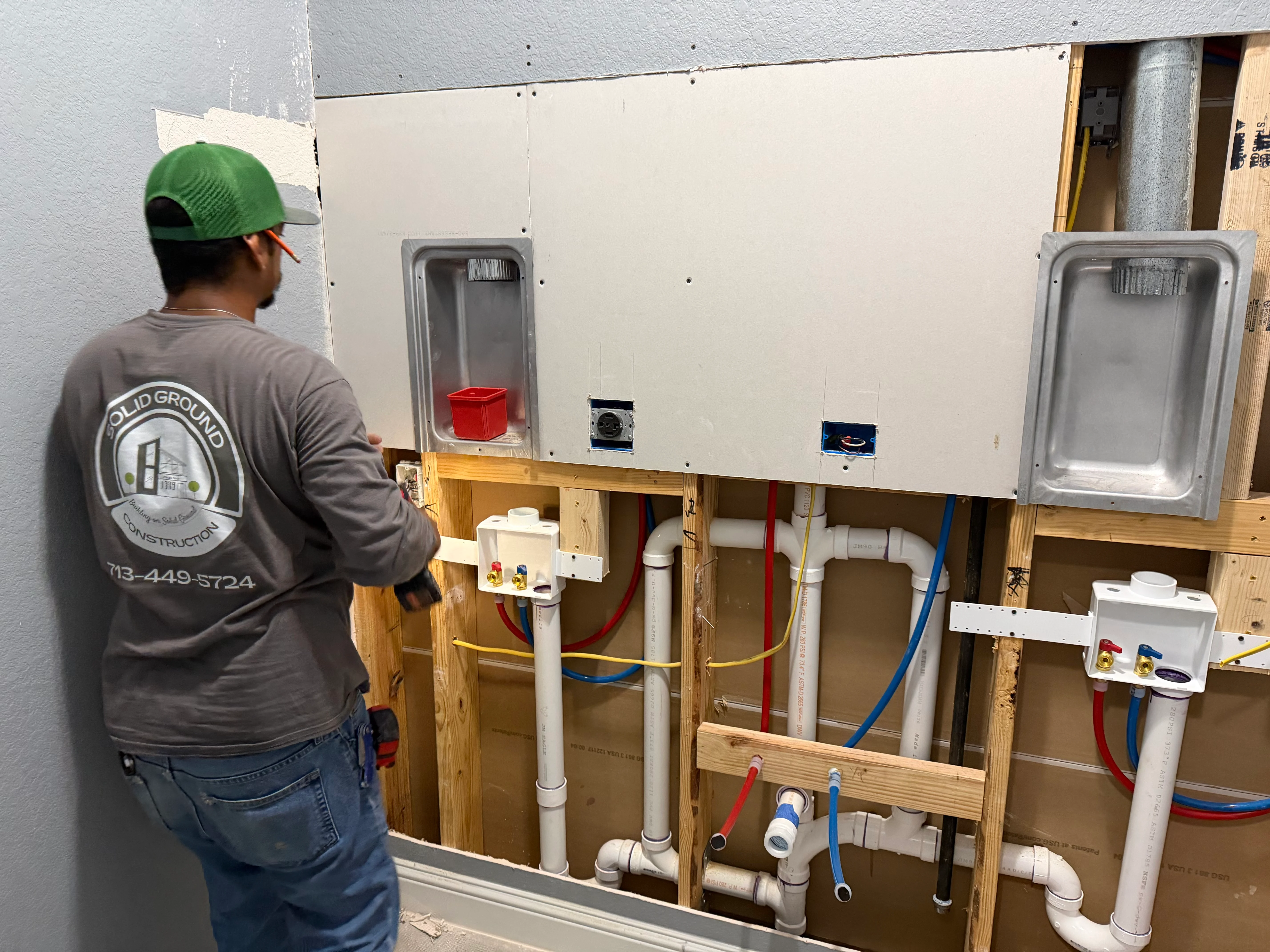 Plumbing rough-in with PVC pipes, supply lines, and fixture boxes in bathroom framing