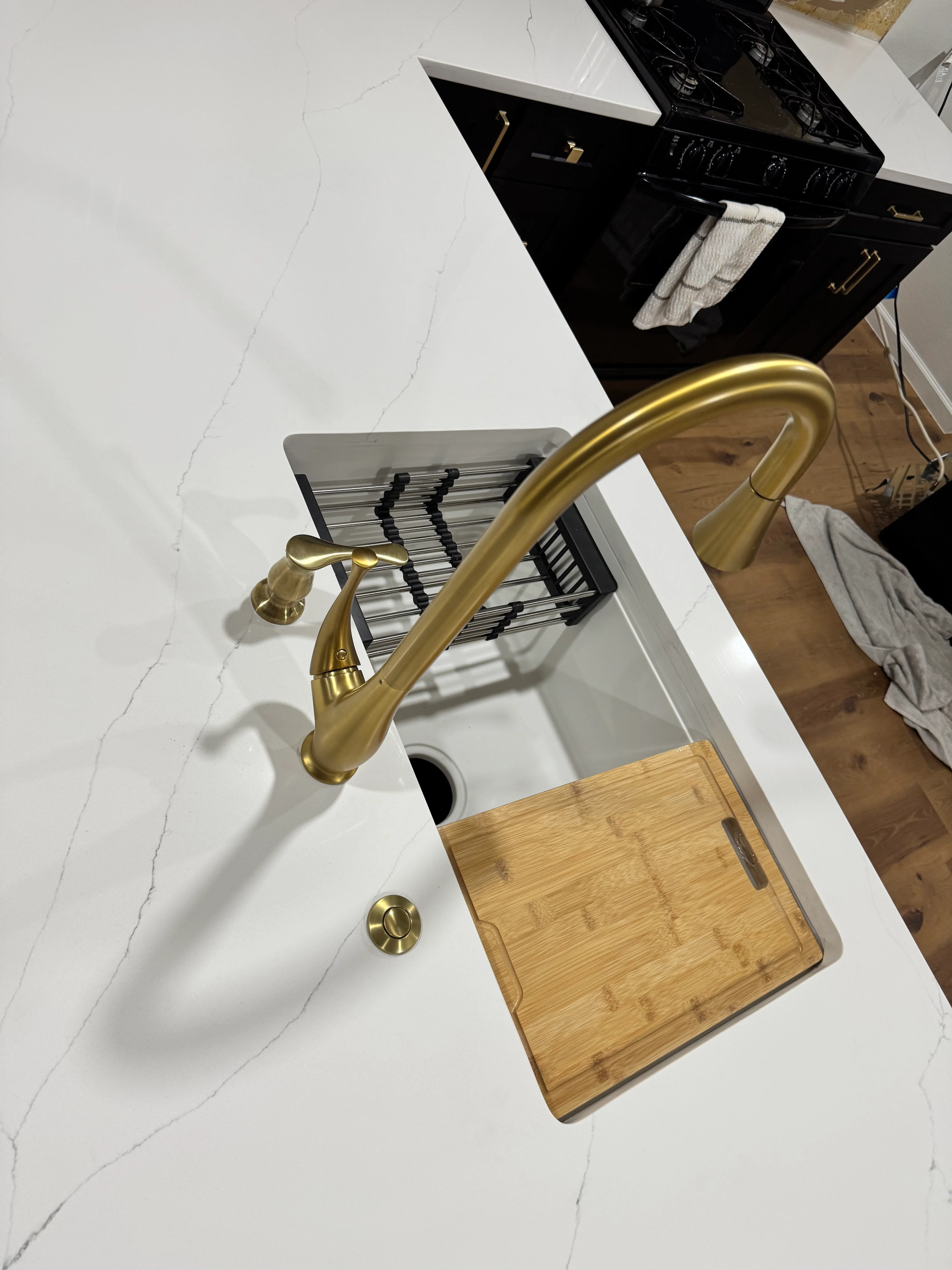 Installed white undermount kitchen sink with brass faucet and bamboo cutting board