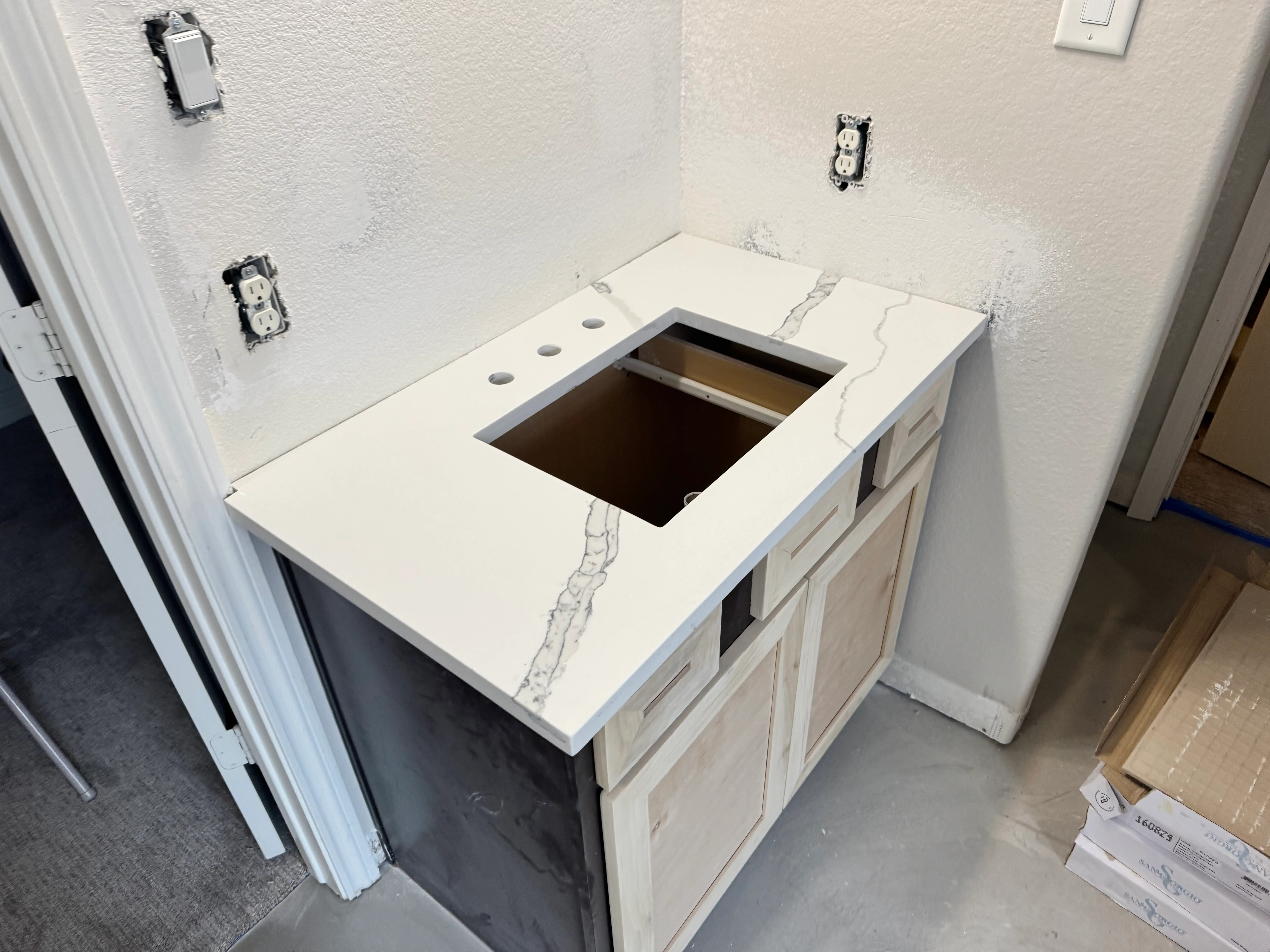 White quartz kitchen countertop with cooktop opening and electrical outlets installed