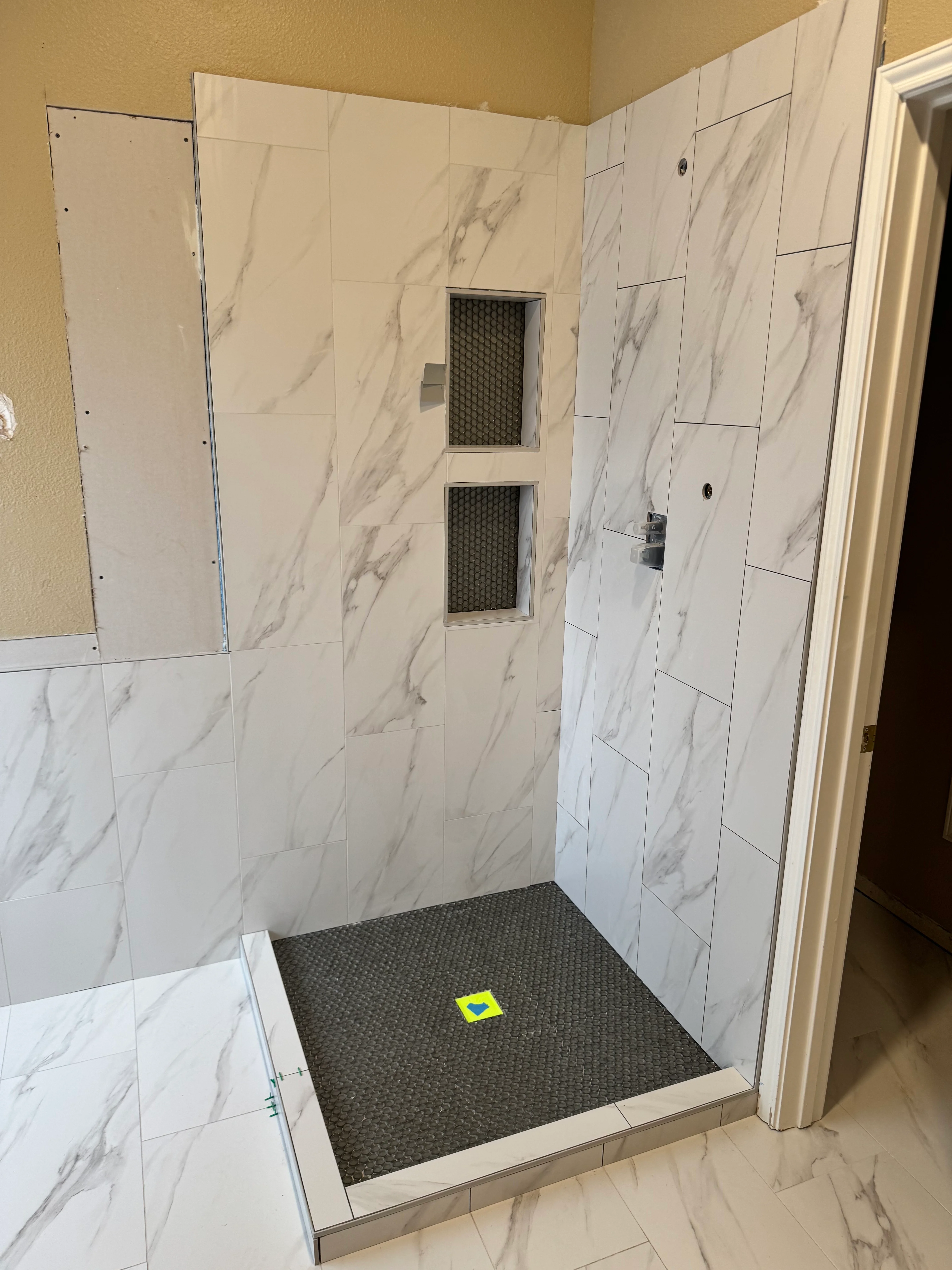 Modern shower enclosure with marble-look tile walls and black textured floor pan