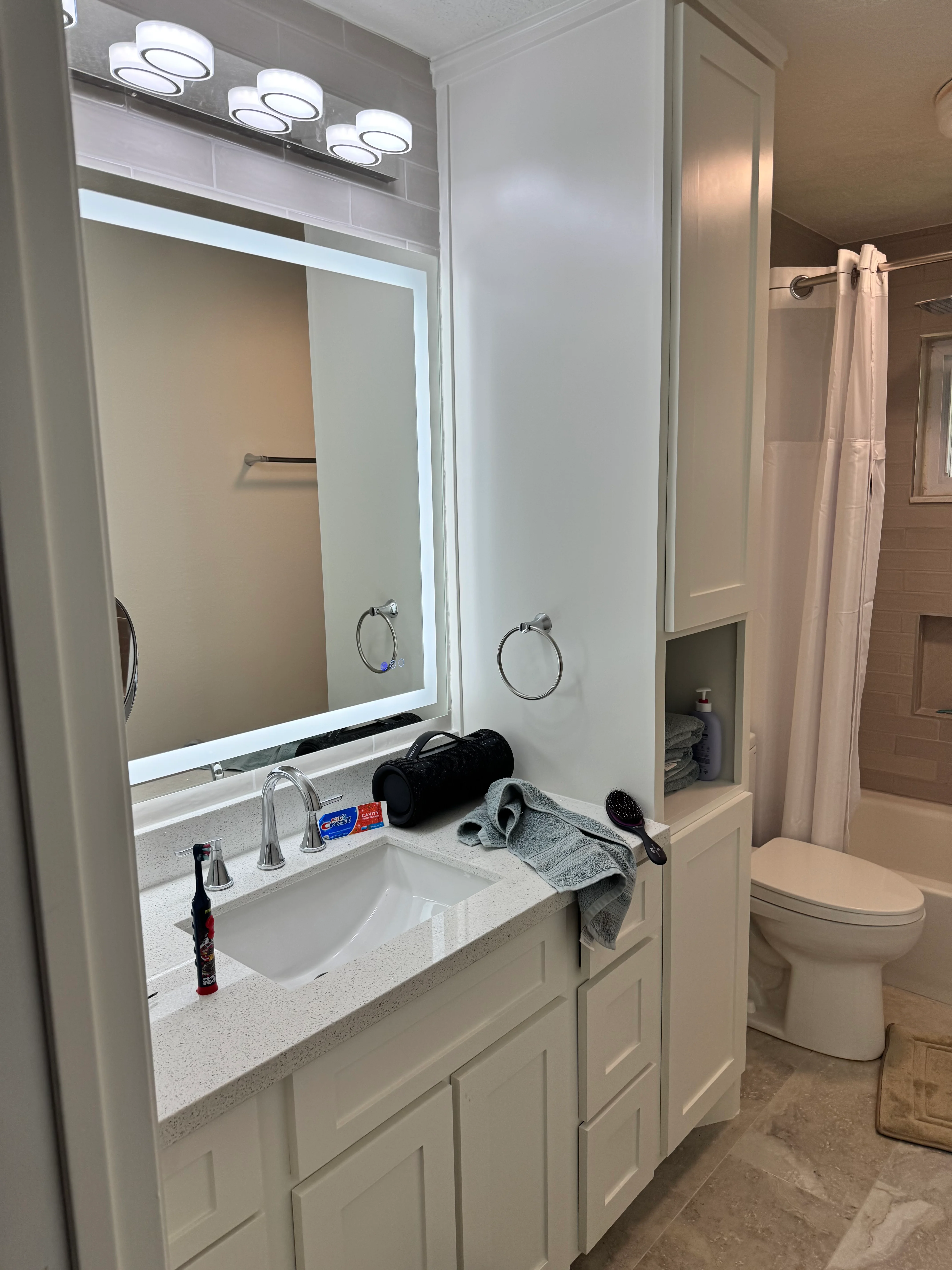 Modern white bathroom vanity with quartz countertop, LED-lit mirror, and chrome fixtures