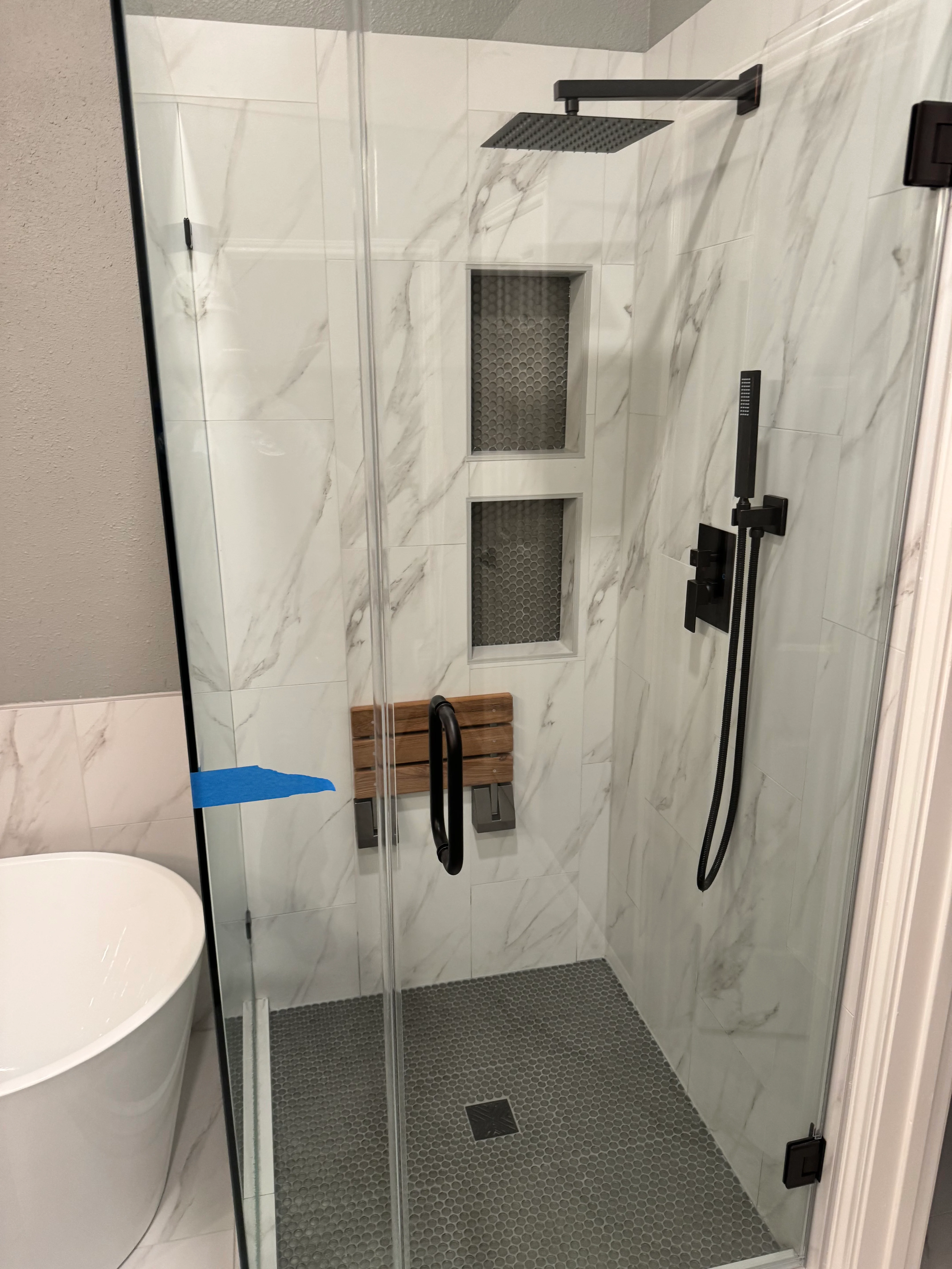 Modern shower enclosure with marble tile walls, dual niches, and black fixtures