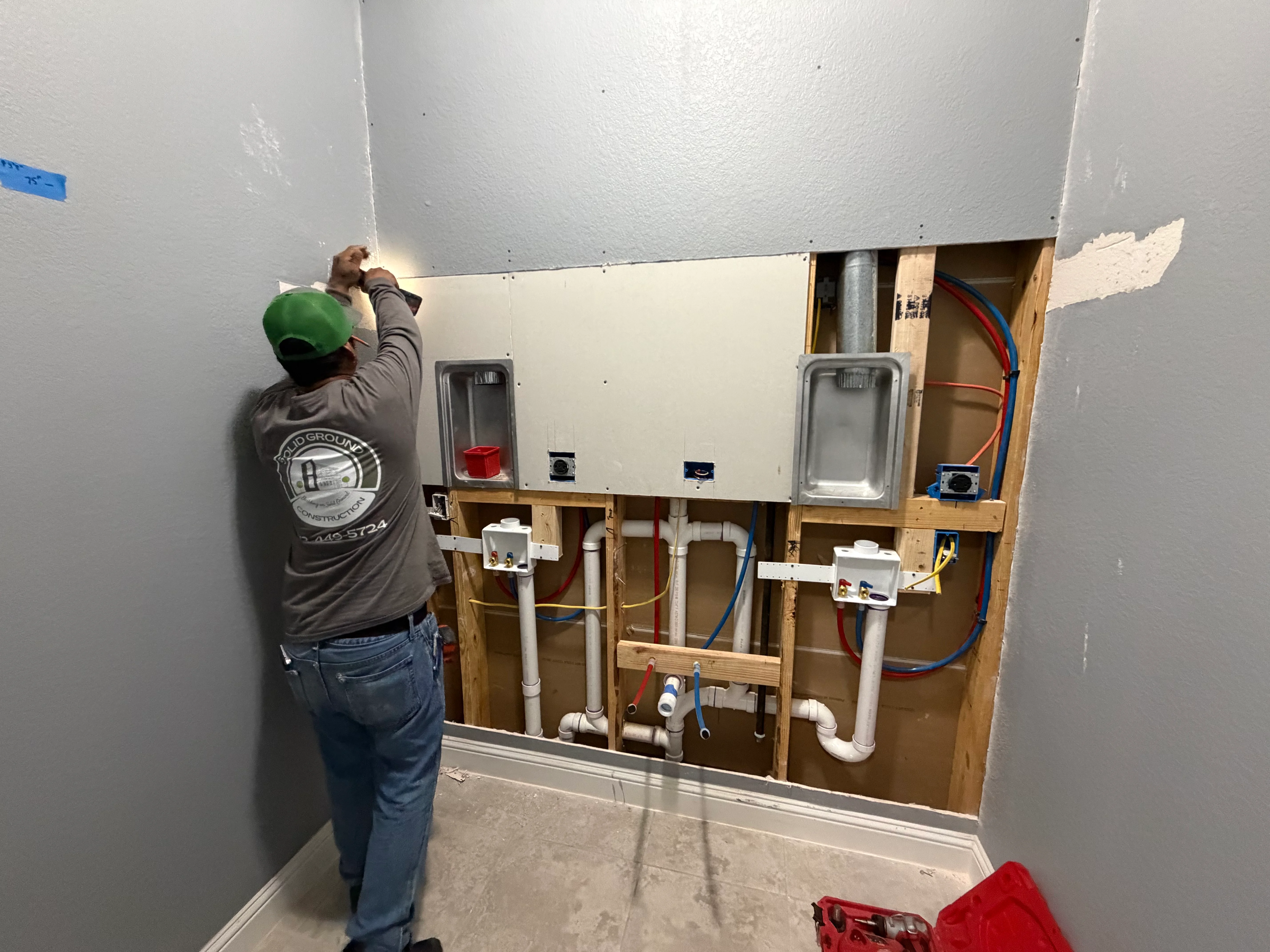 Plumber installing bathroom rough-in plumbing with PVC drains and copper supply lines in framed wall