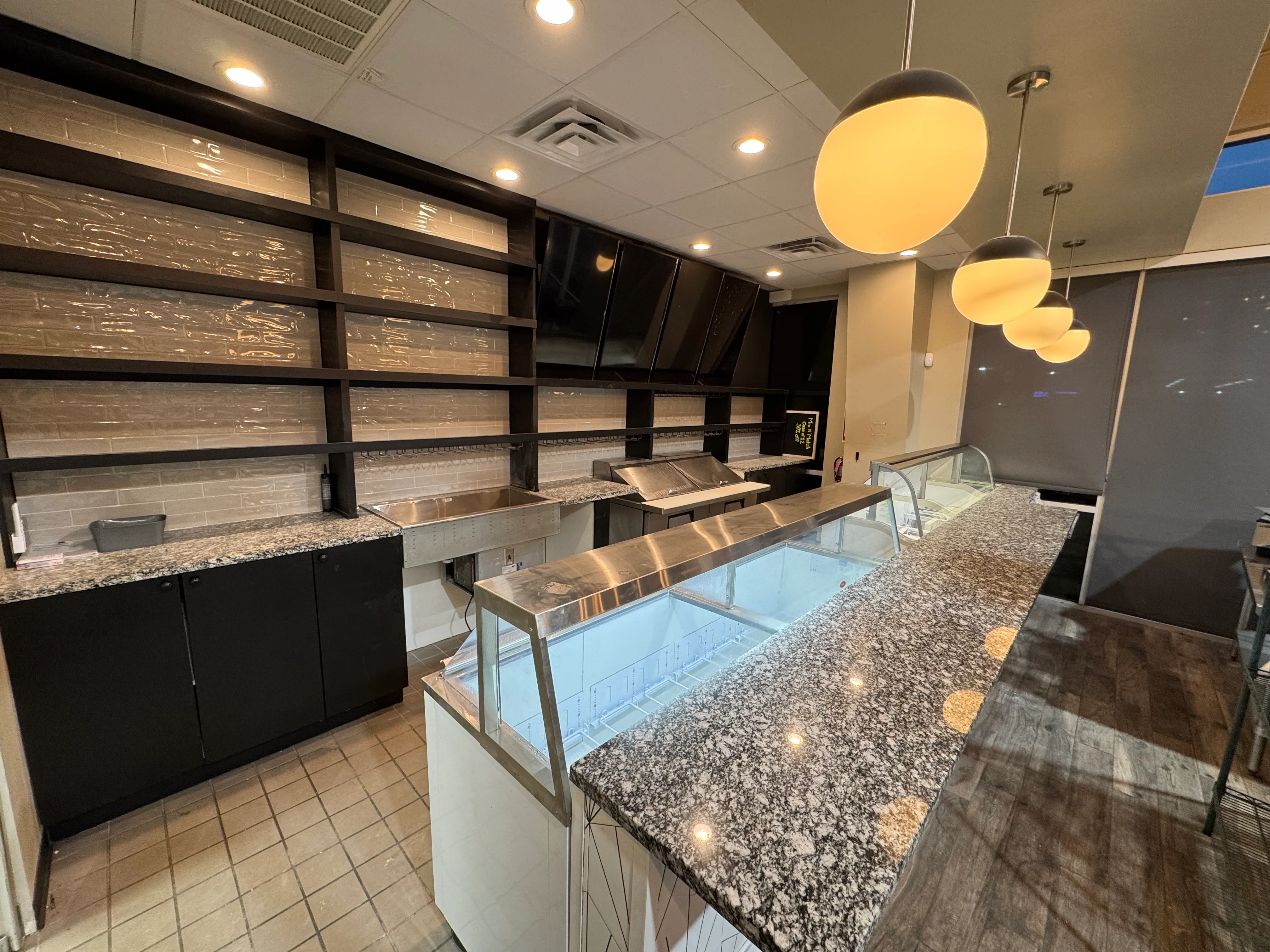 Modern commercial bakery interior with black cabinetry, granite counters, and stainless steel display cases