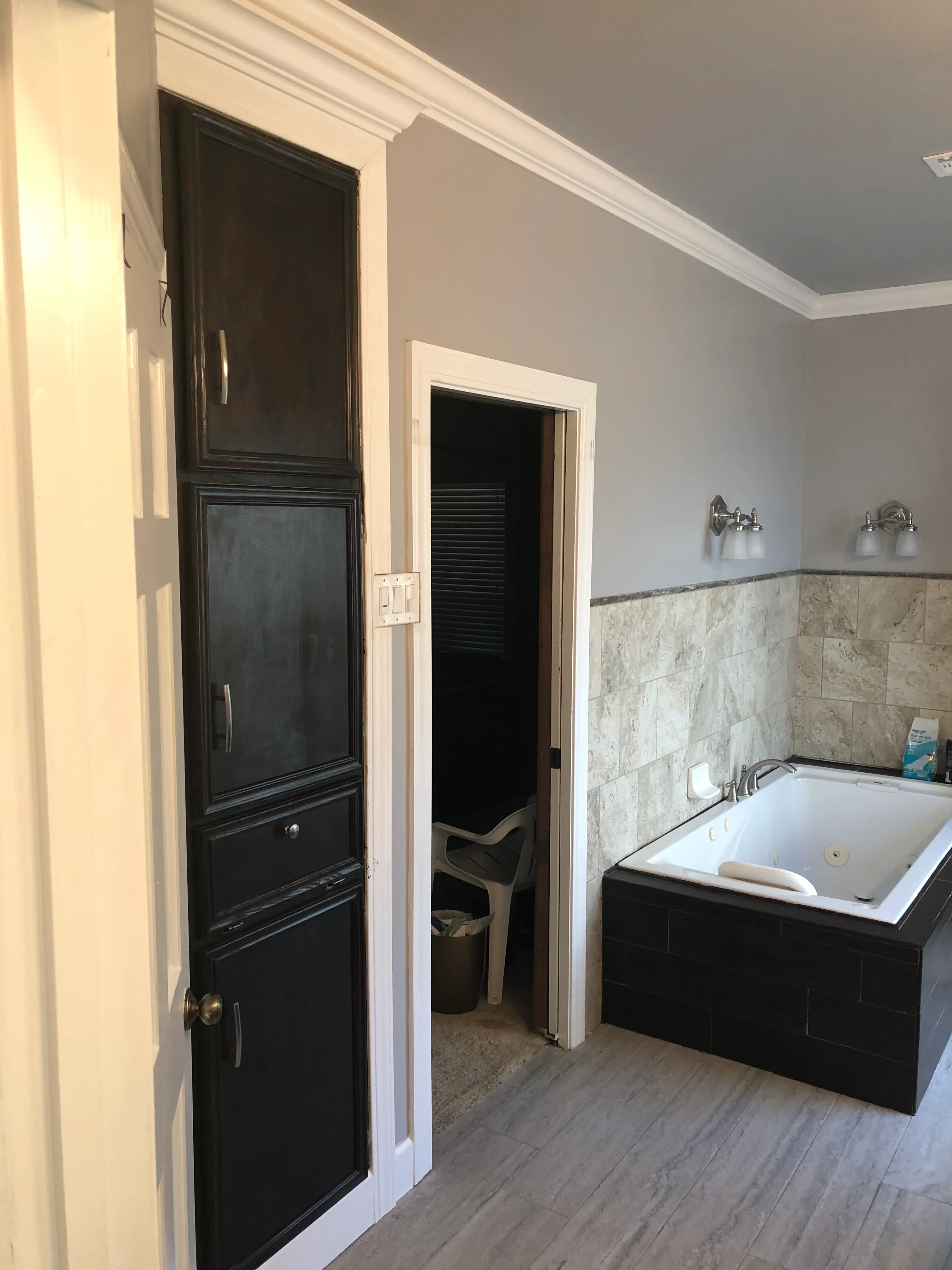 Modern bathroom with black cabinetry, marble tile backsplash, and white soaking tub