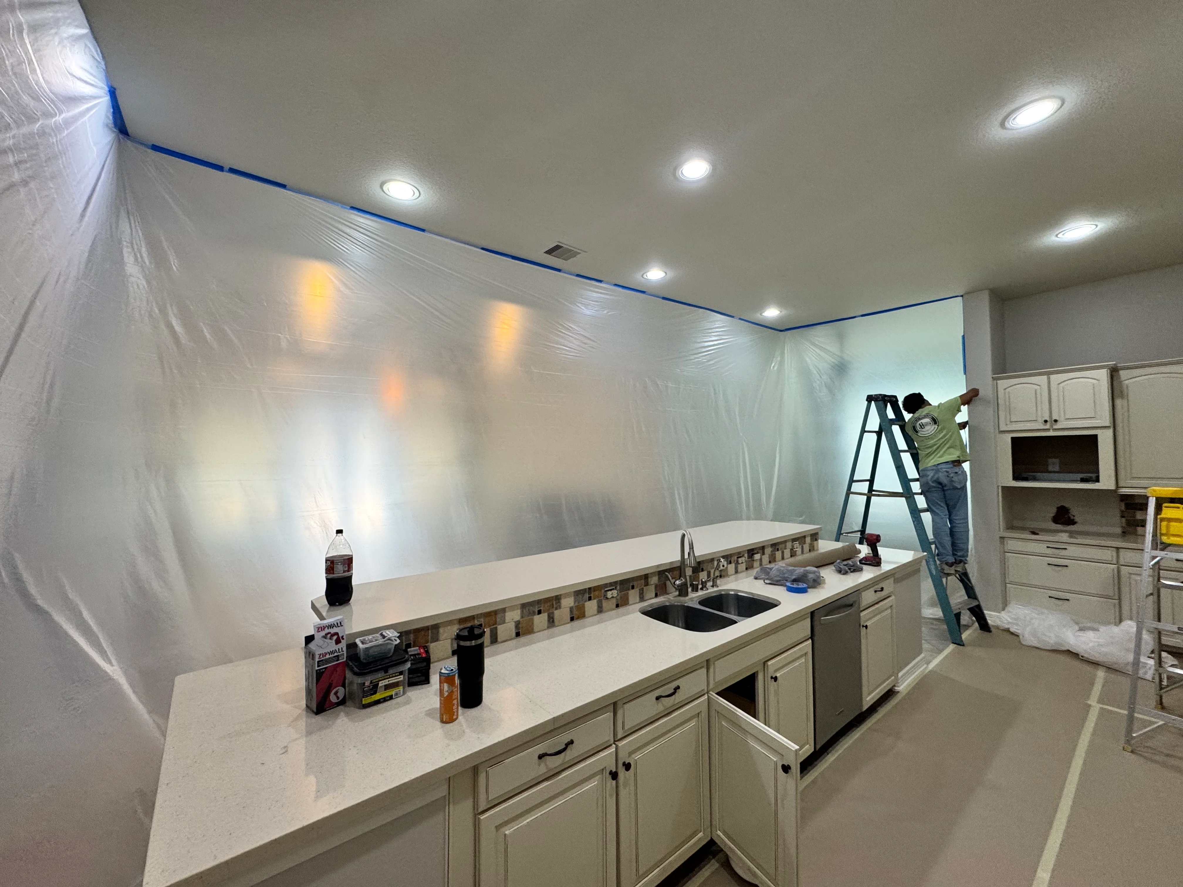 Kitchen remodel in progress with recessed lighting, white drywall, and cream cabinetry