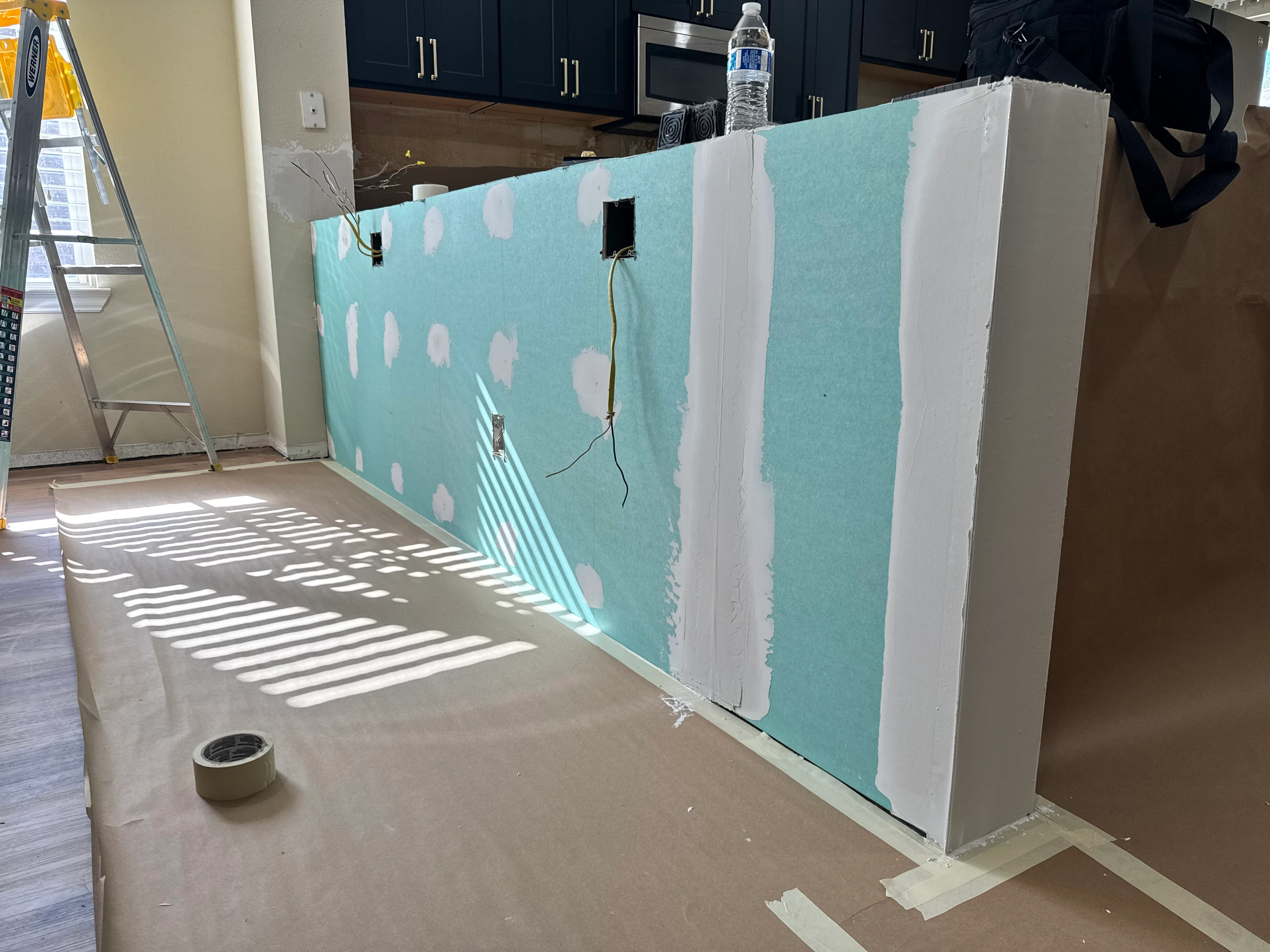 Kitchen remodel in progress with turquoise drywall, white joint compound patches, and electrical outlet boxes installed