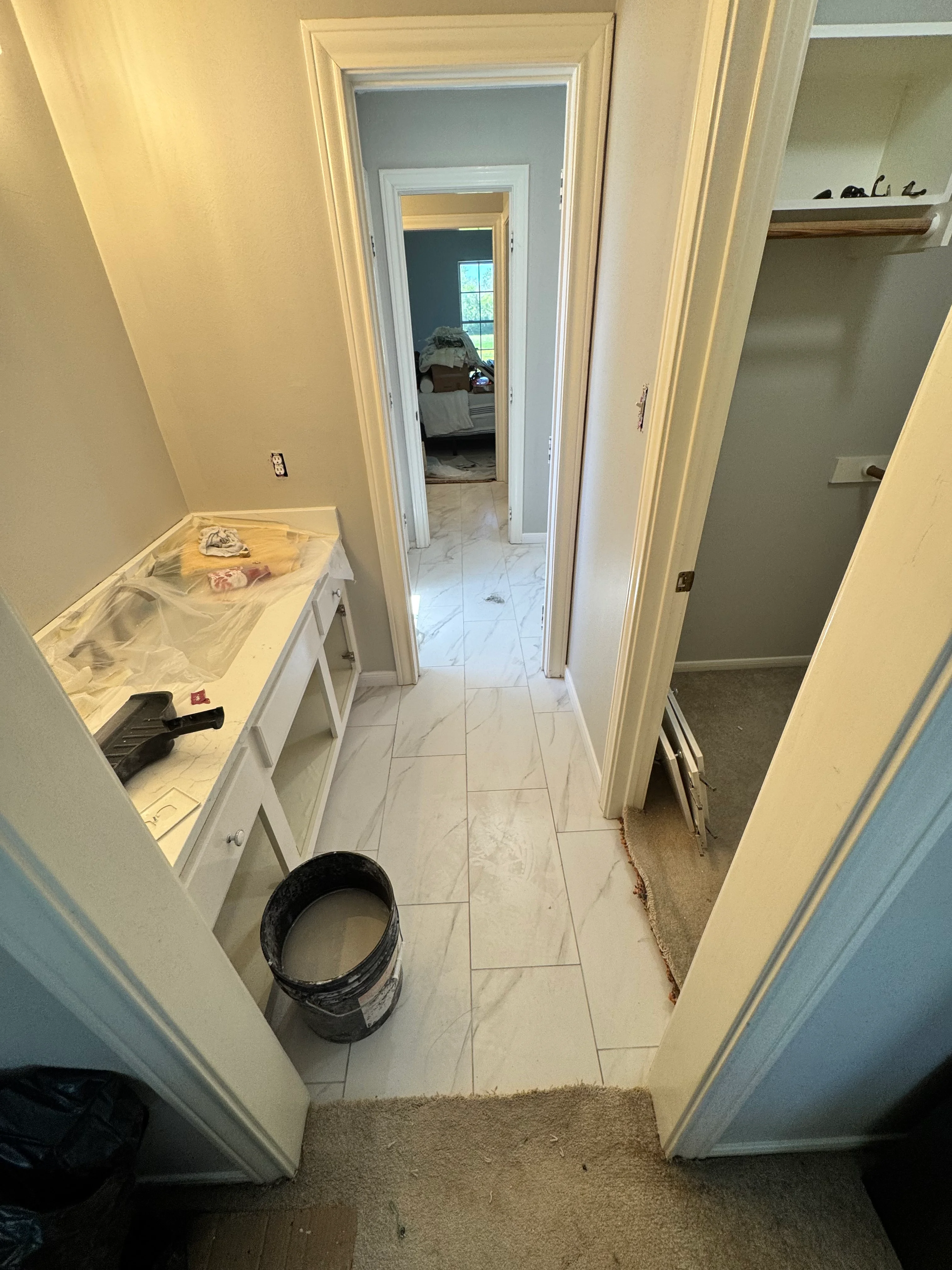 Master bathroom renovation in progress with new marble tile flooring and white cabinetry