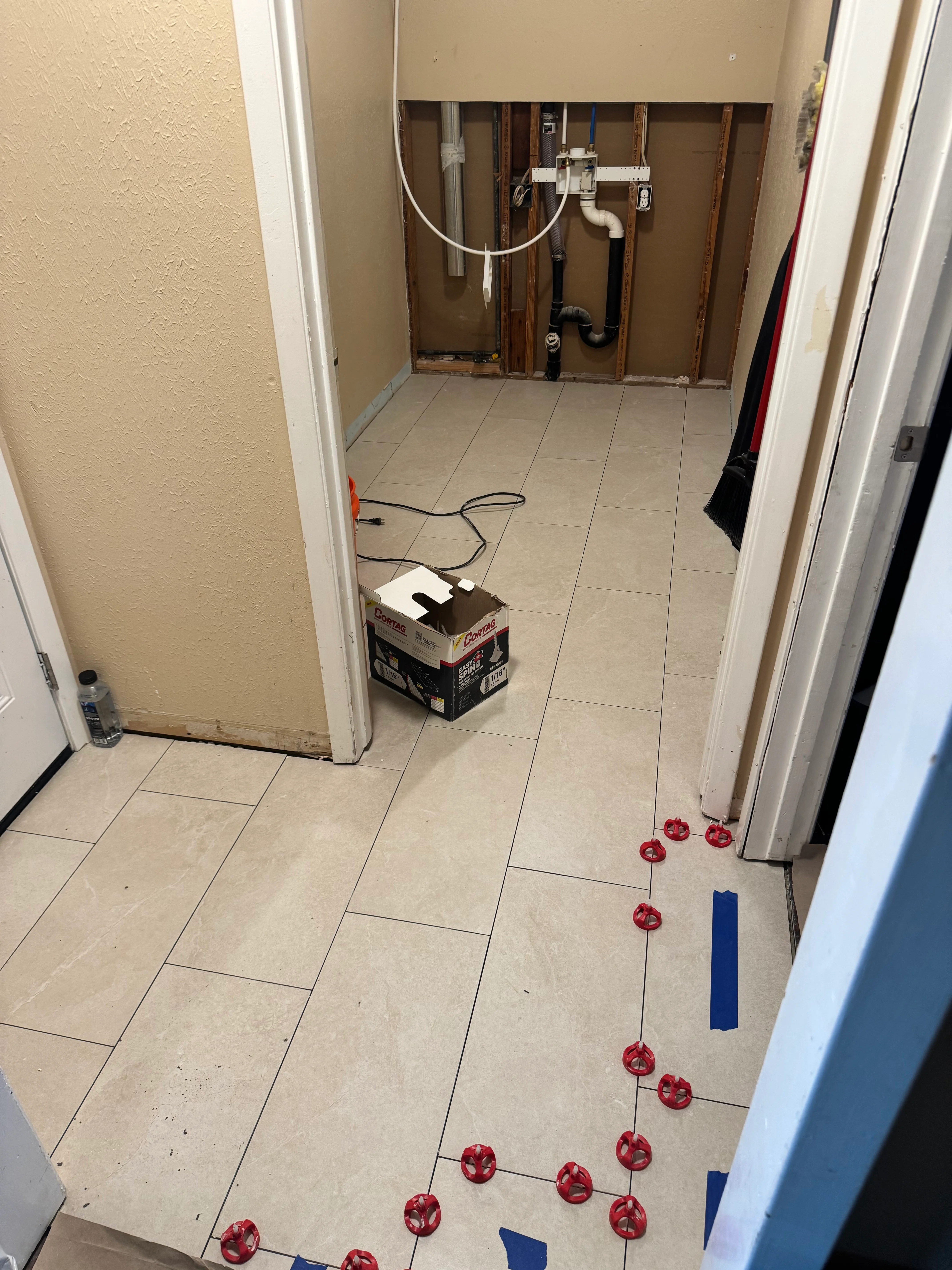 Bathroom under renovation with new plumbing lines and ceramic tile flooring layout