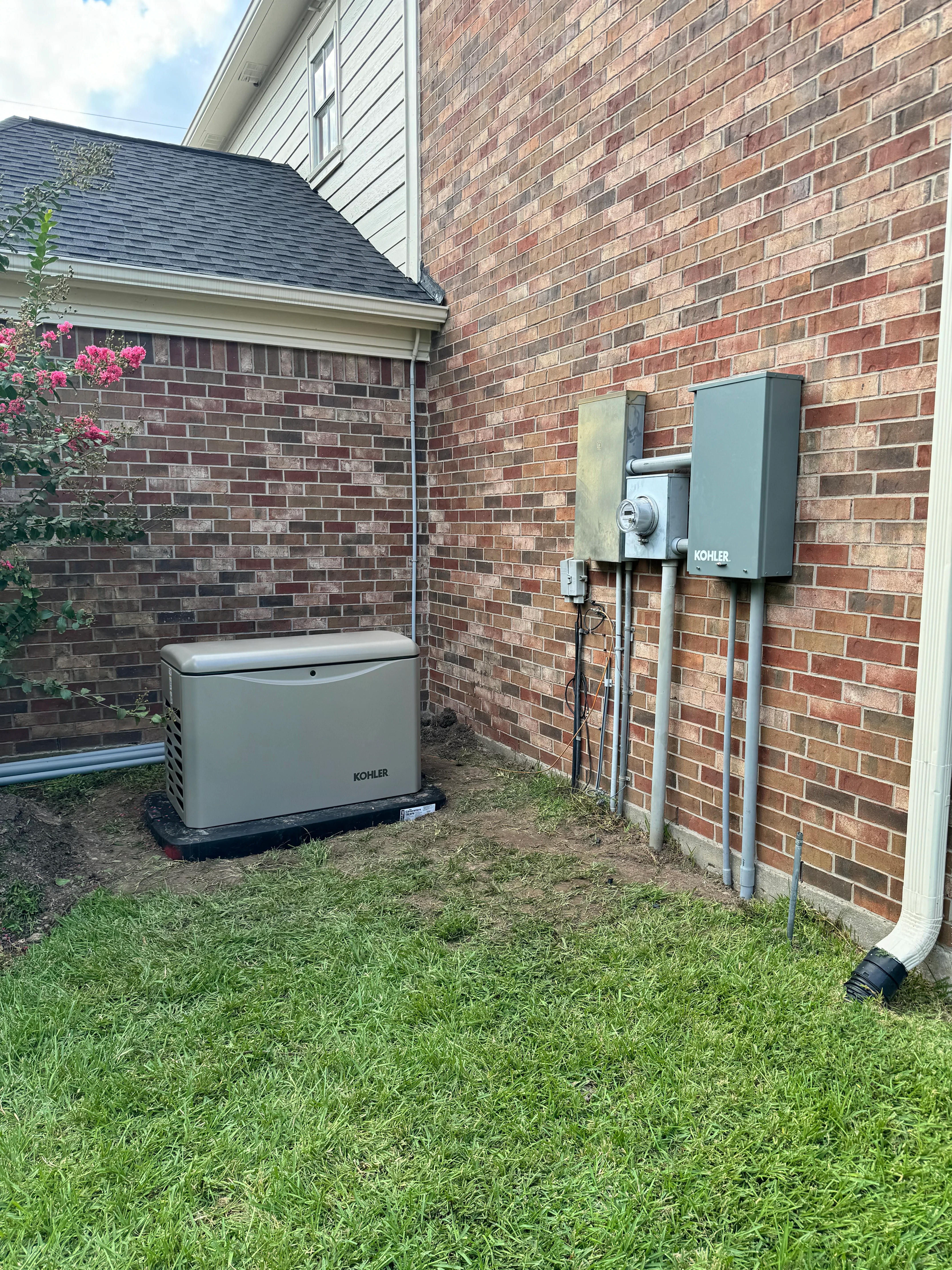 Kohler standby generator and transfer switch installed against brick home exterior