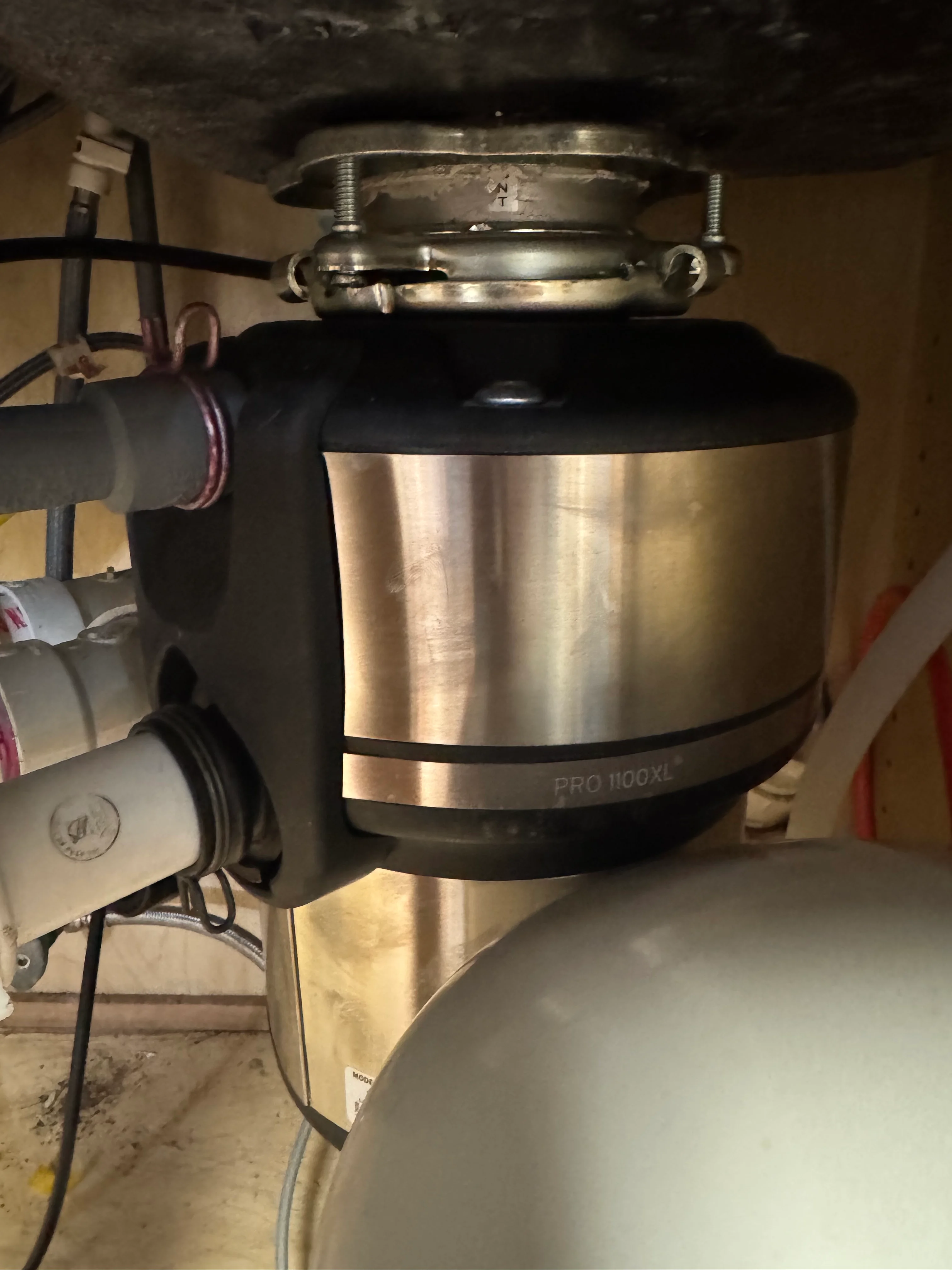 Stainless steel Pro 1100XL garbage disposal installed under kitchen sink with mounting hardware
