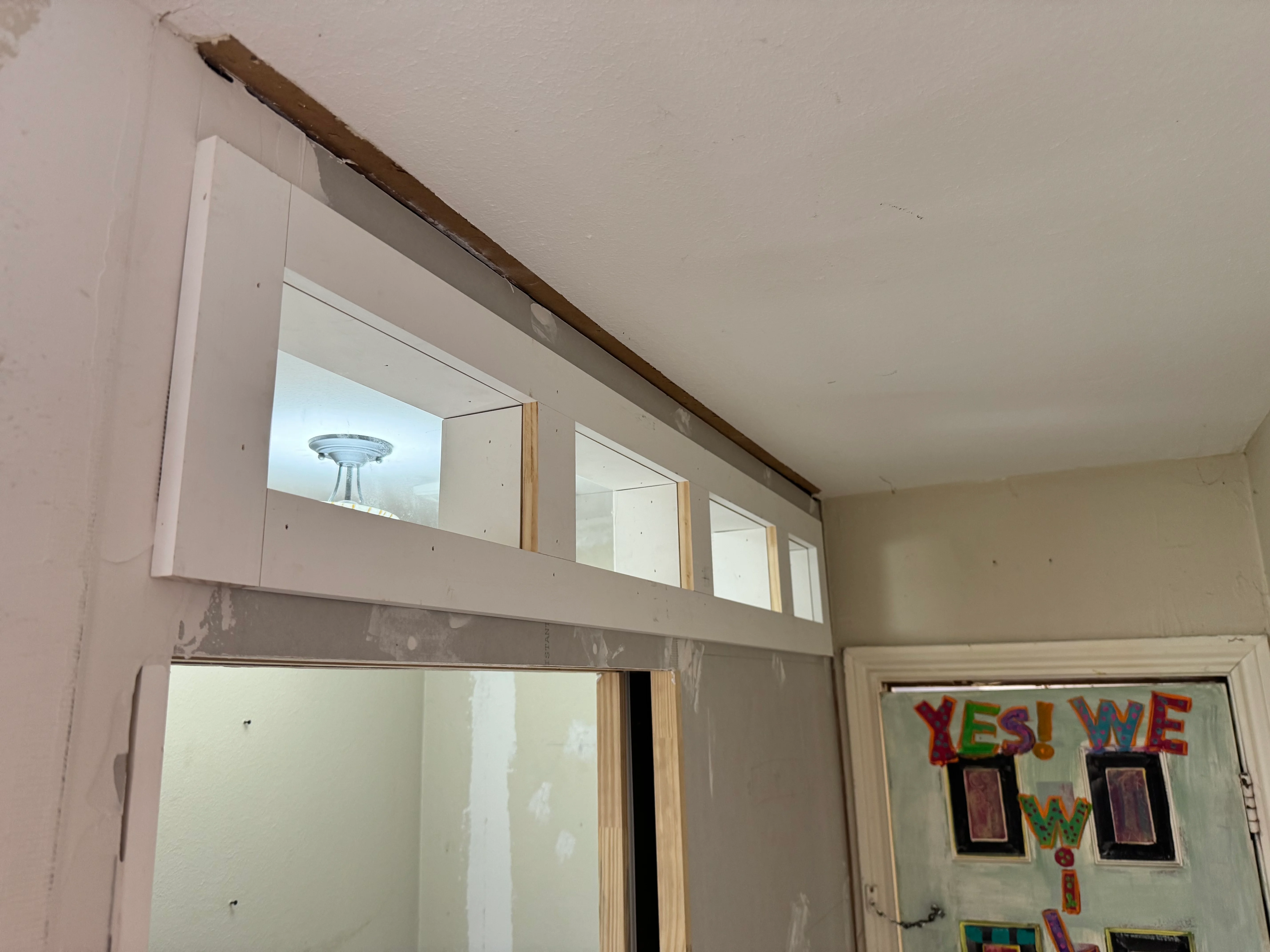 Interior framing with drywall, wood-framed windows, and exposed beam during remodeling