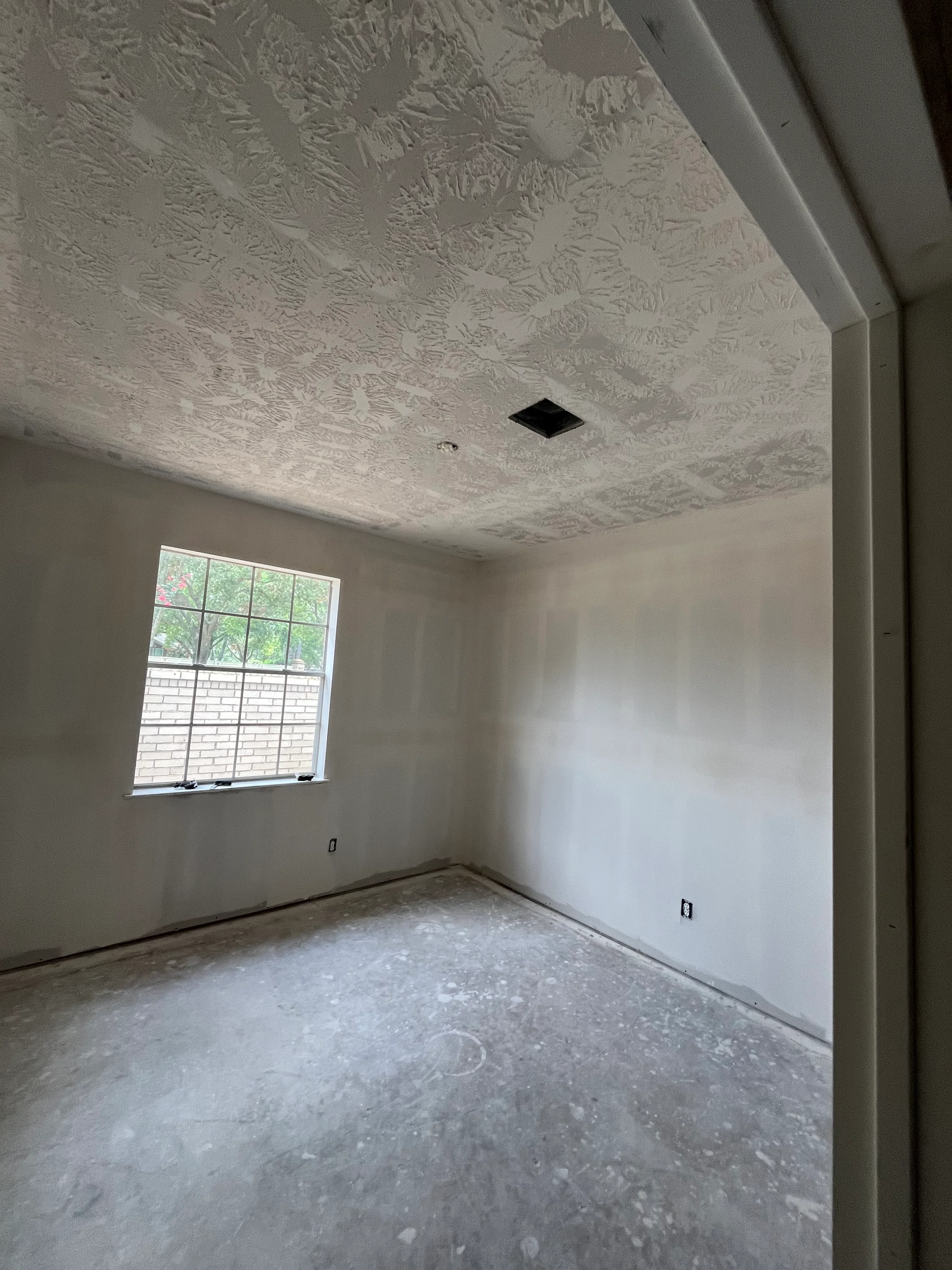 Empty room with white drywall walls, textured ceiling, and recessed light opening