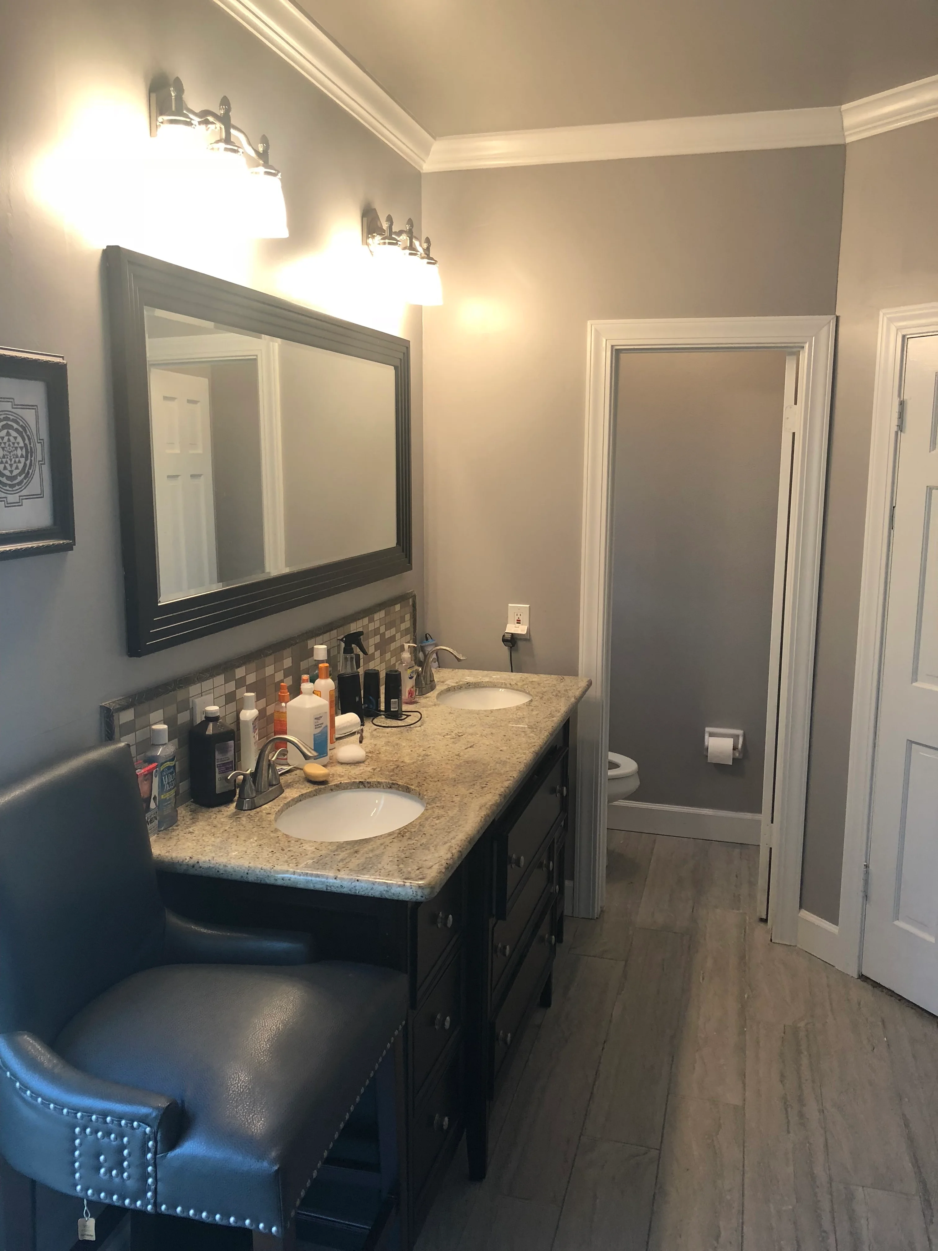 Modern bathroom vanity with dark cabinets, granite countertop, and dual sinks with chrome fixtures