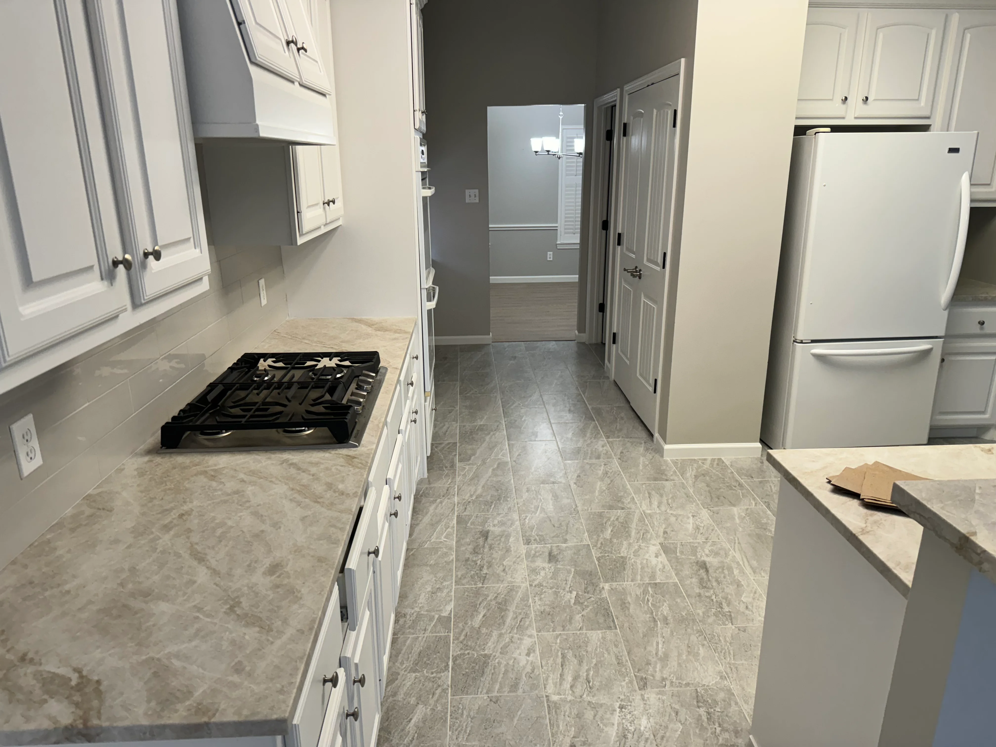 Modern kitchen with white cabinets, gray quartz counters, and gray tile flooring