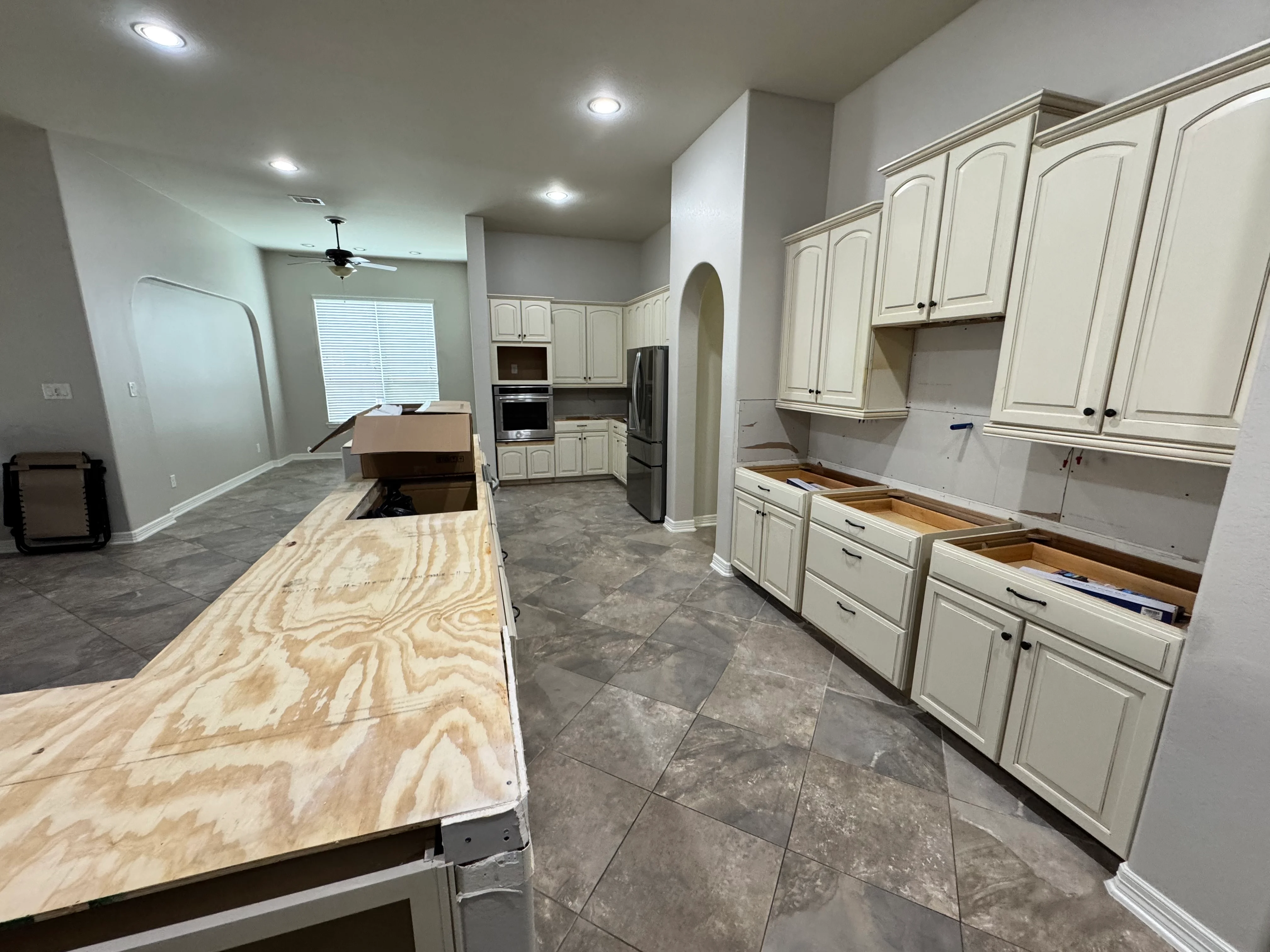 Kitchen remodel in progress with cream cabinetry, islands, and stainless steel appliances
