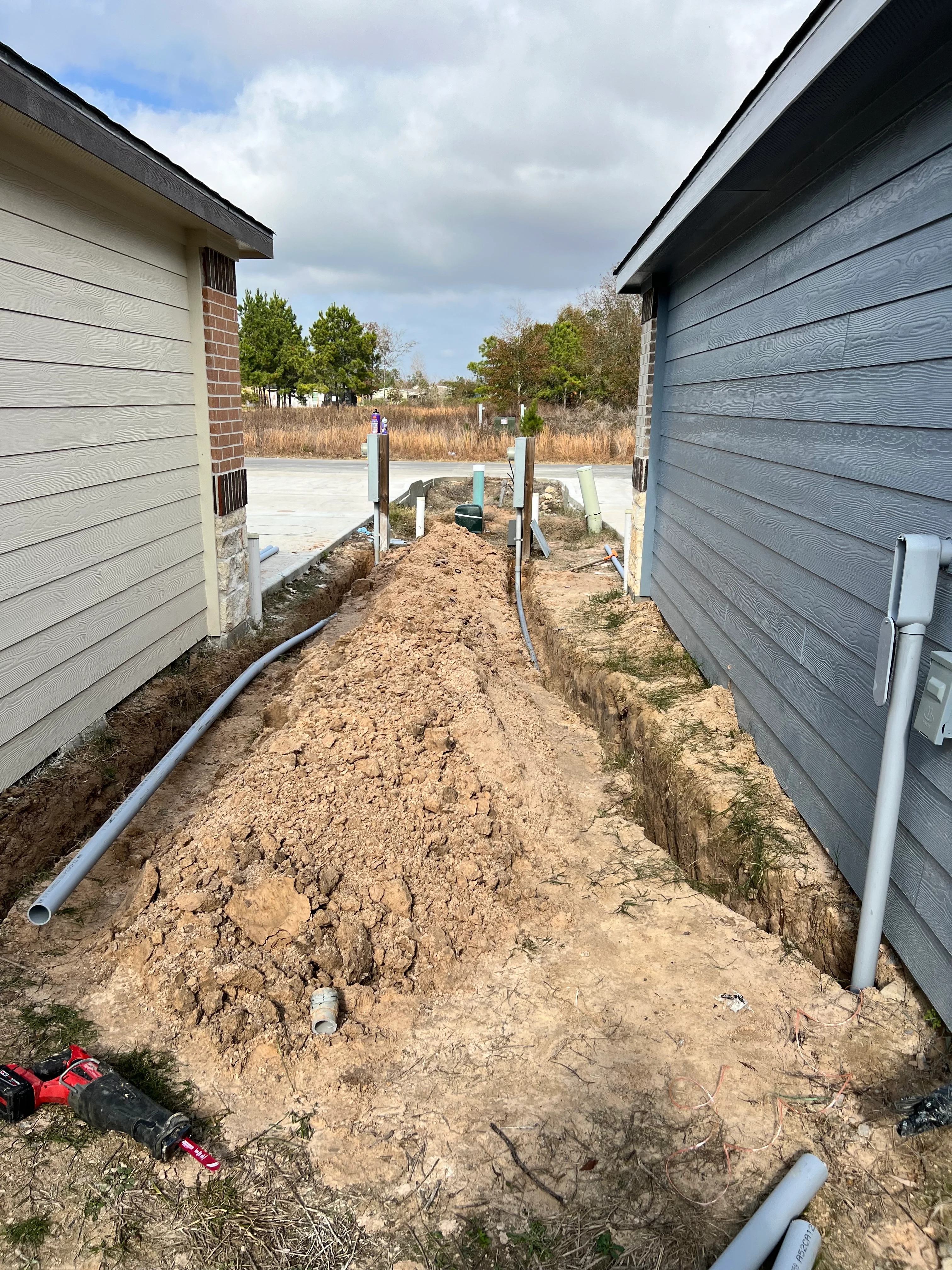 Underground PVC utility lines installed in trenches between two new homes during construction phase
