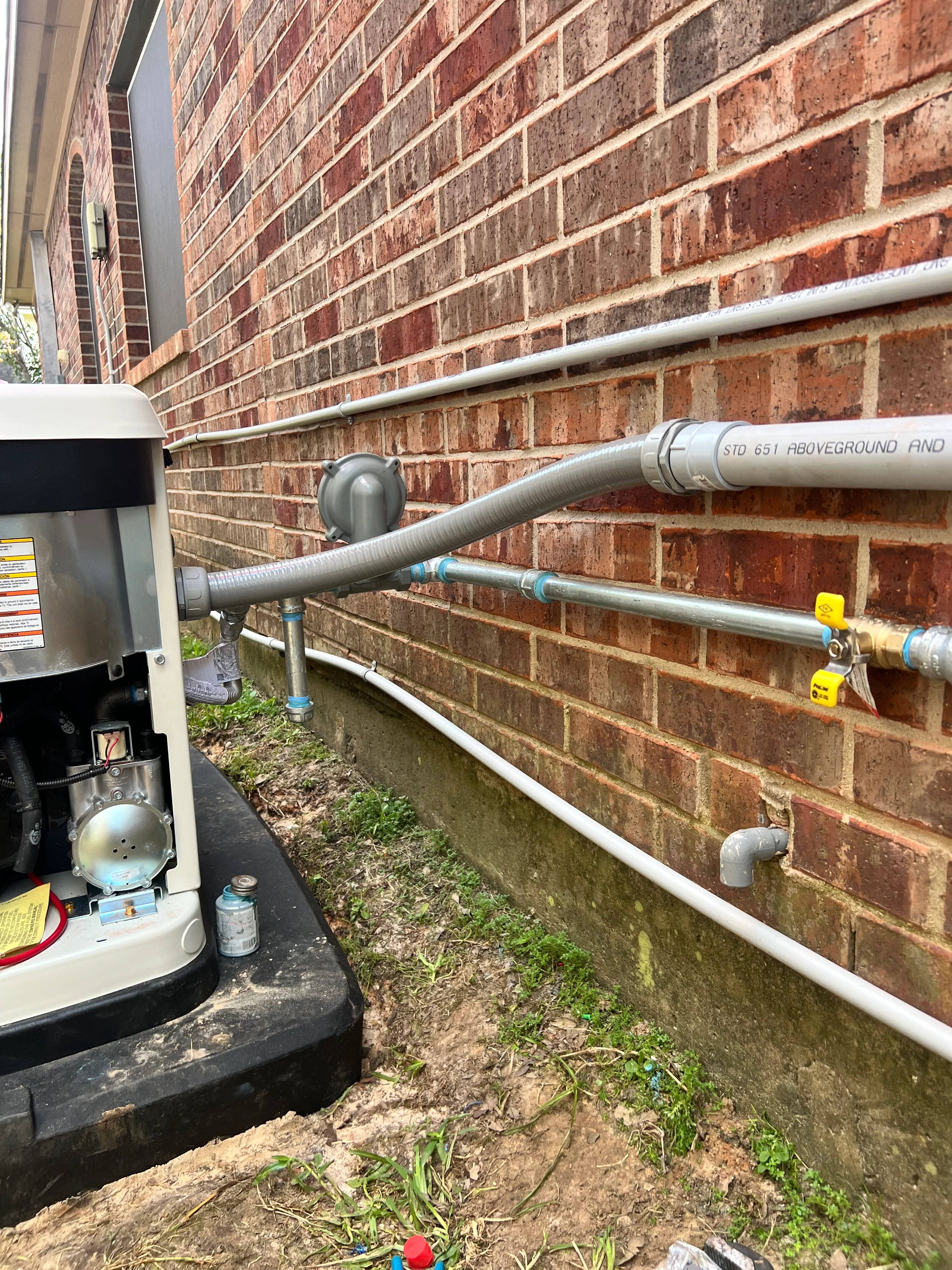 Underground drainage system with PVC pipes and brass valves installed against brick foundation
