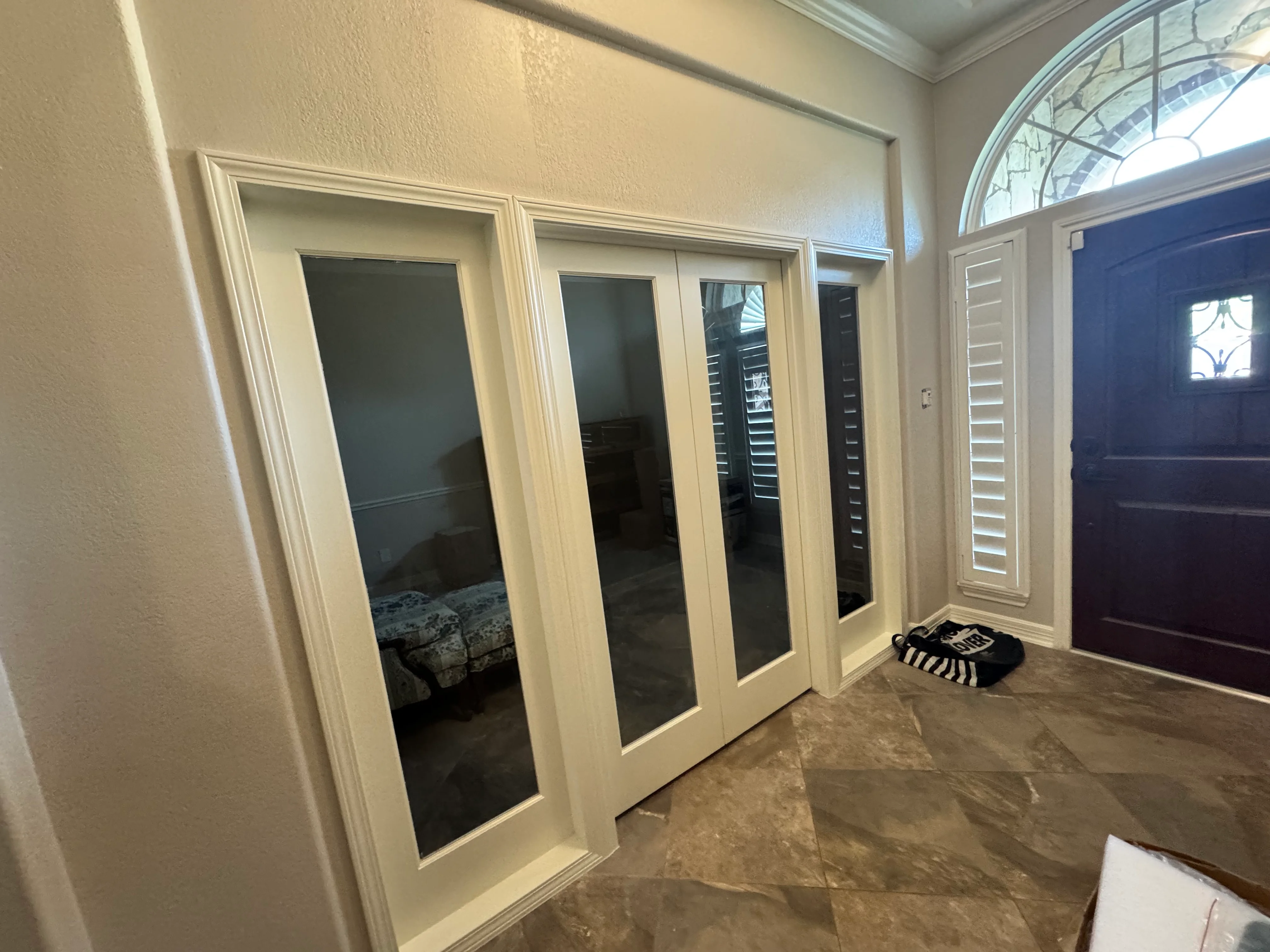 Master bedroom with four cream French doors and glass panels opening to walk-in closet space