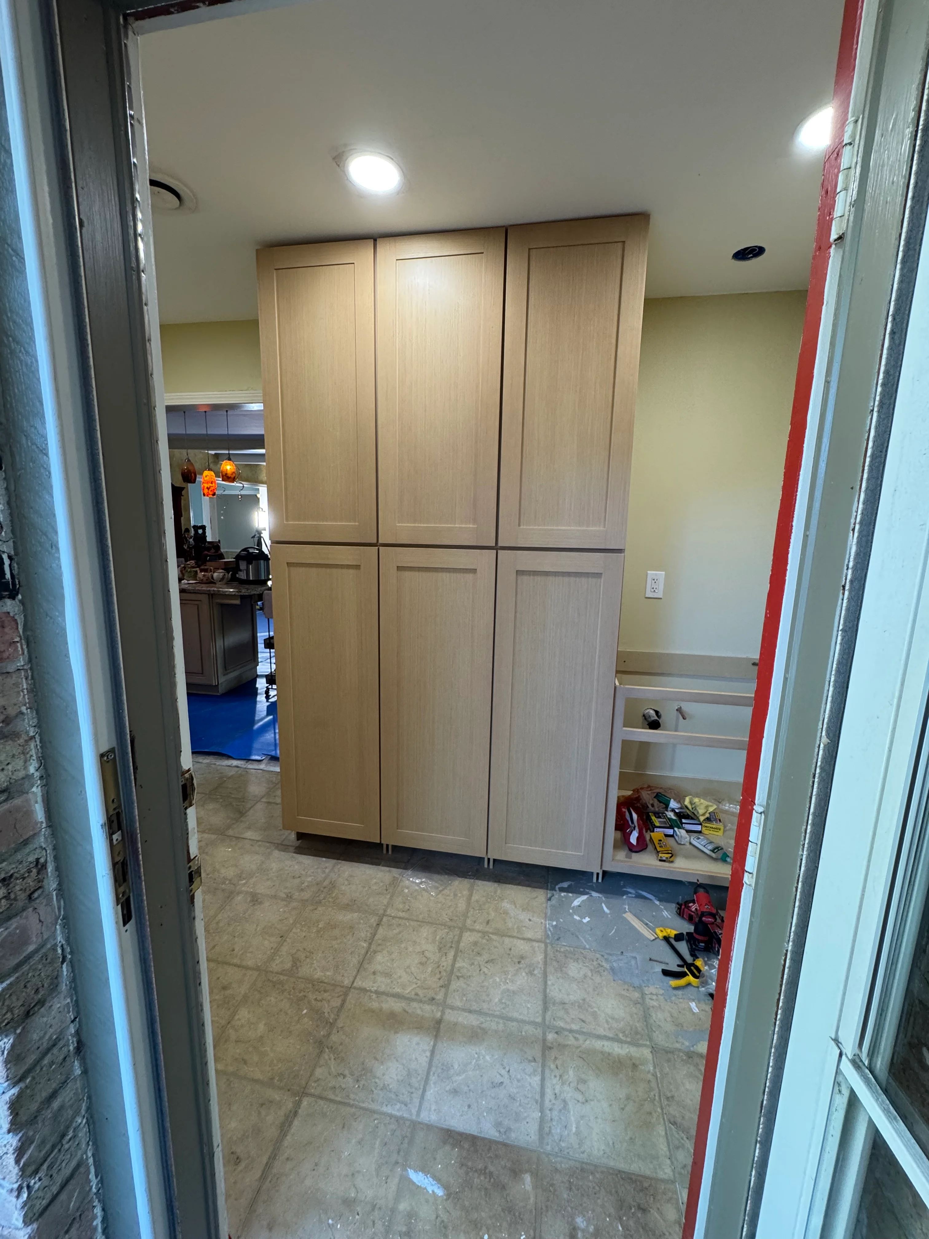 Three tall wooden storage cabinets with recessed panel doors installed in a garage with tile flooring