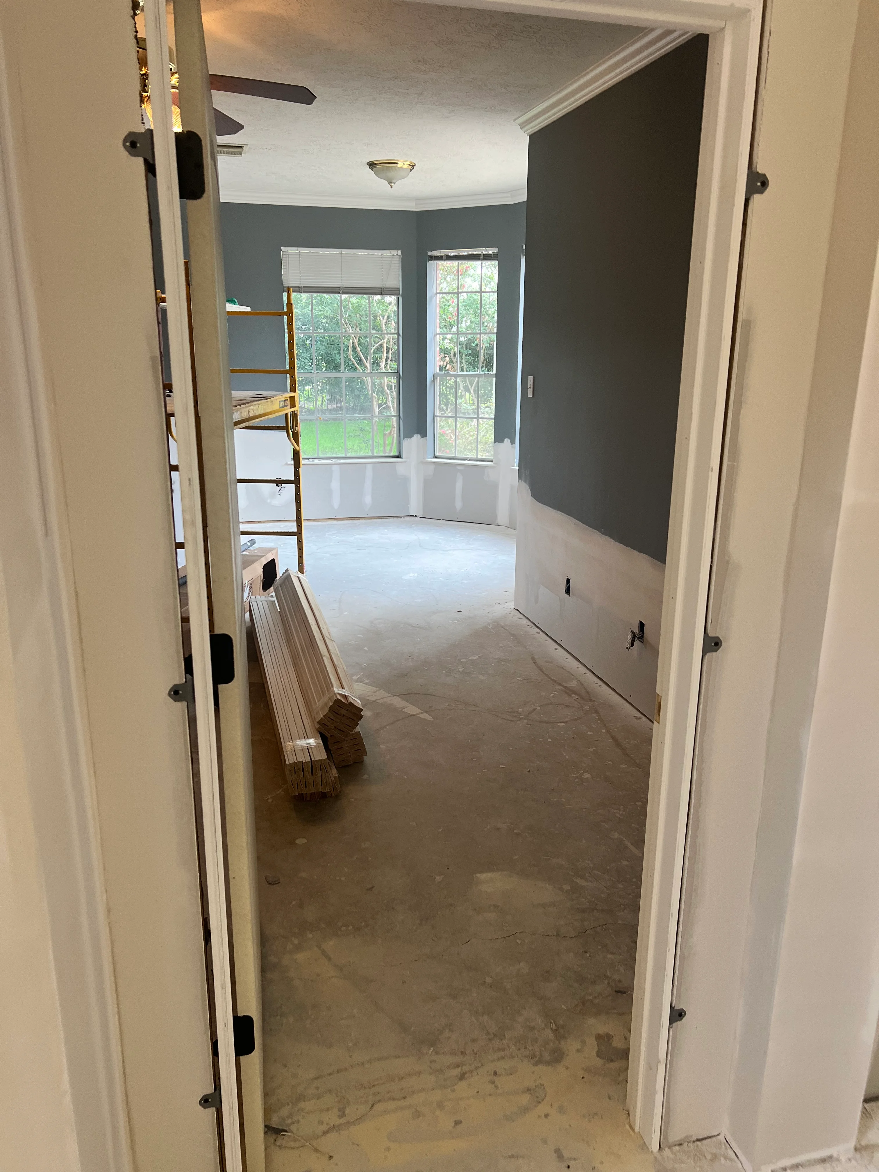 New bedroom addition with white and gray paint, large windows, and drywall finishing in progress