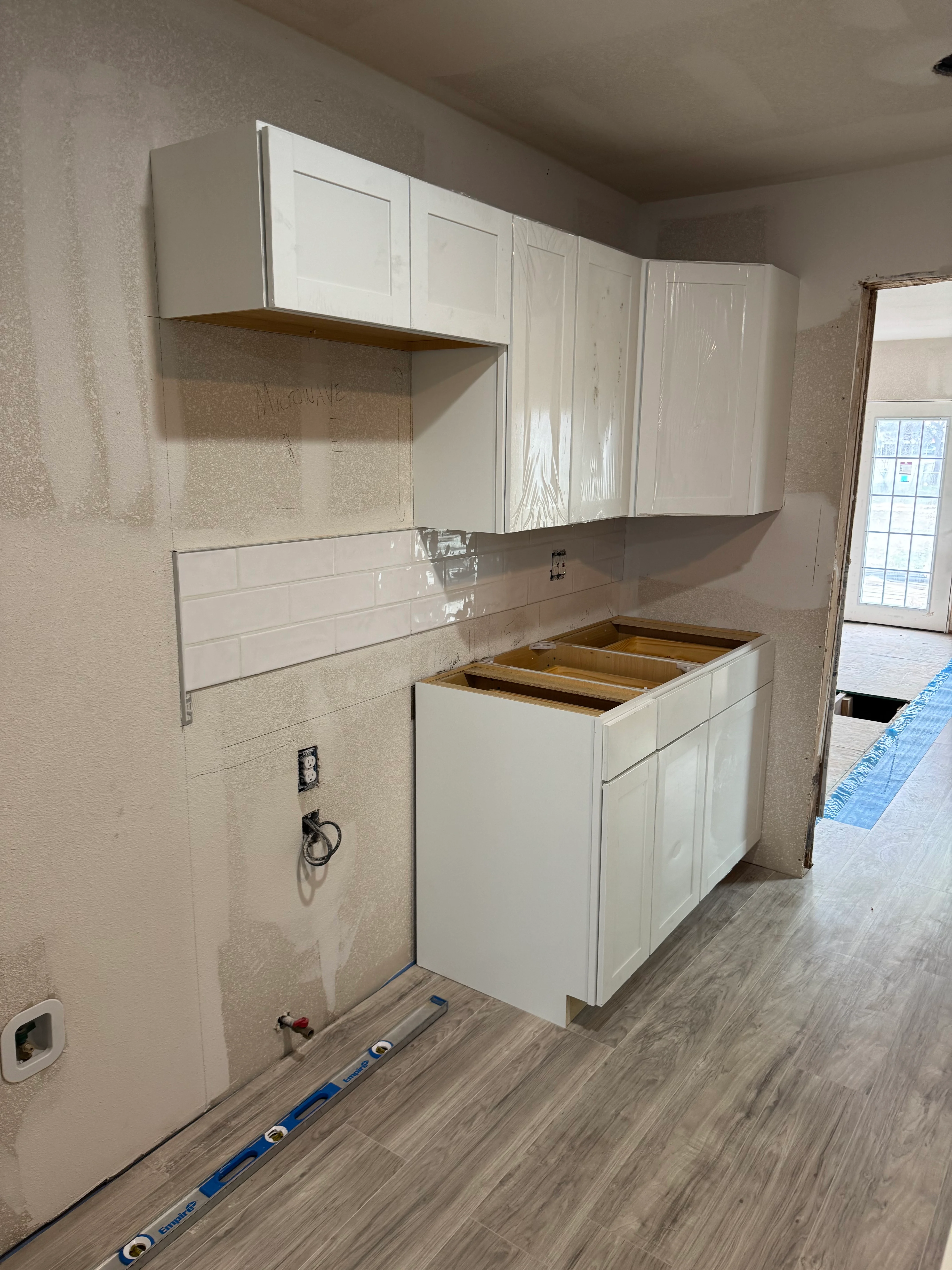 White kitchen cabinets with subway tile backsplash during installation in Spring, TX