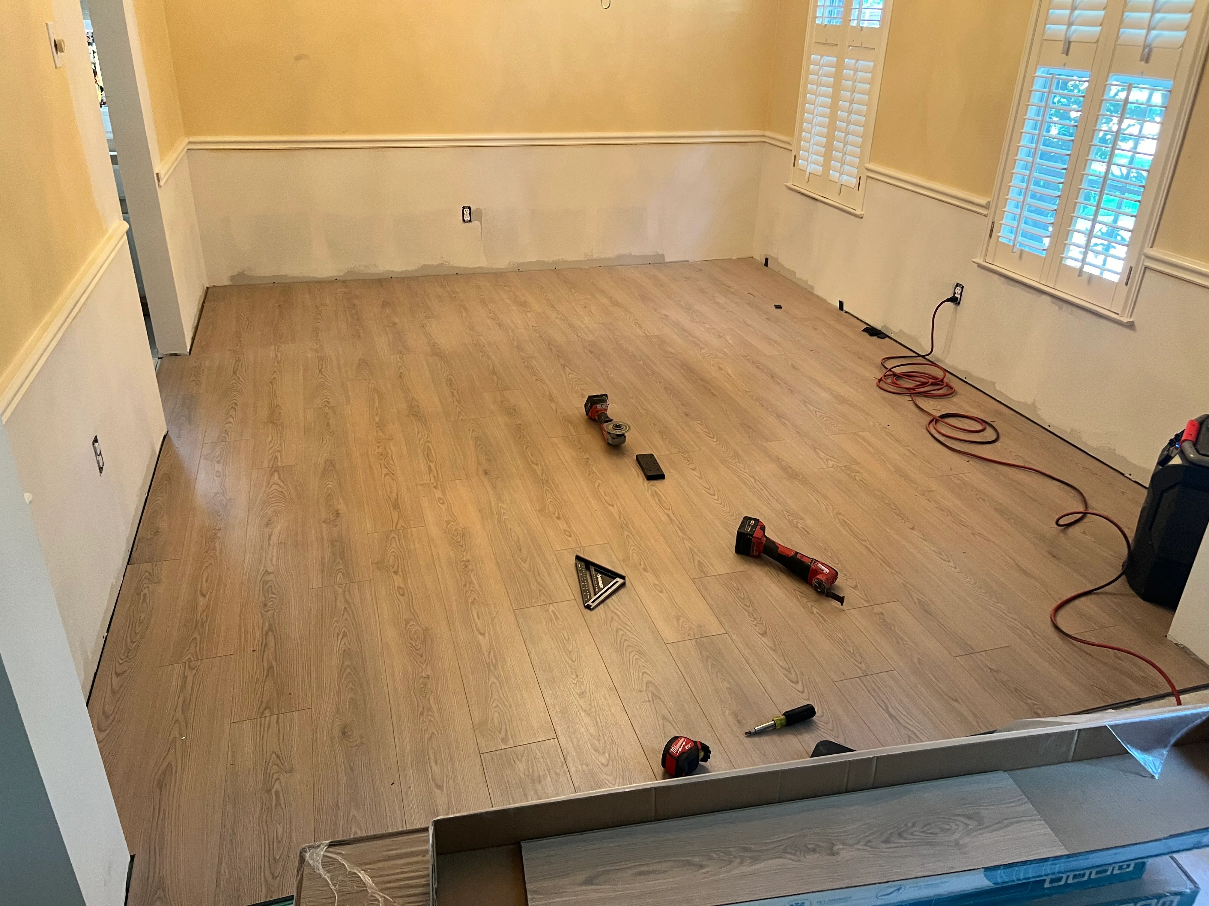Luxury vinyl plank flooring installation in progress with warm oak finish and chair rail molding