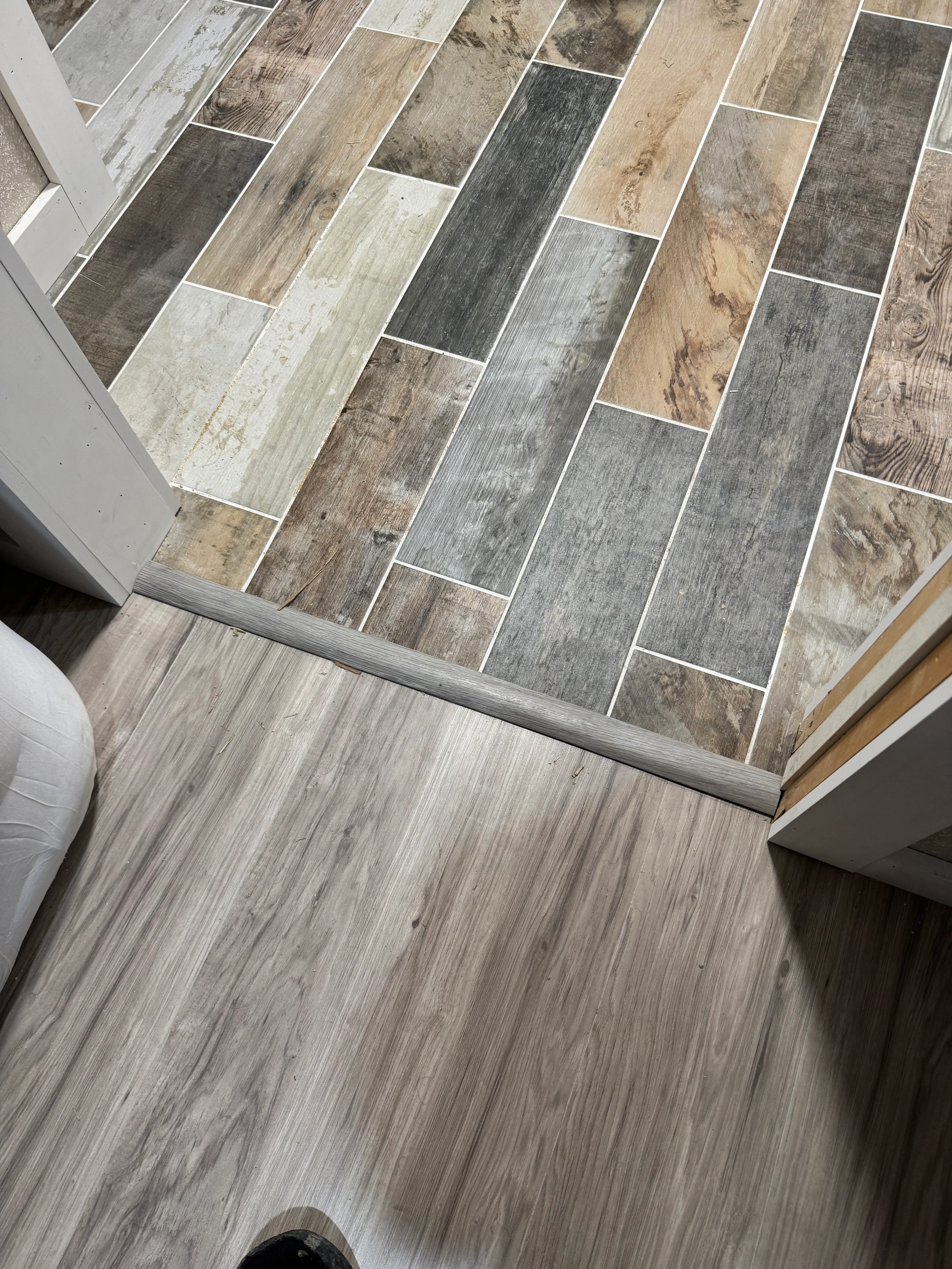 Herringbone pattern luxury vinyl plank flooring in mixed wood tones with white grout lines