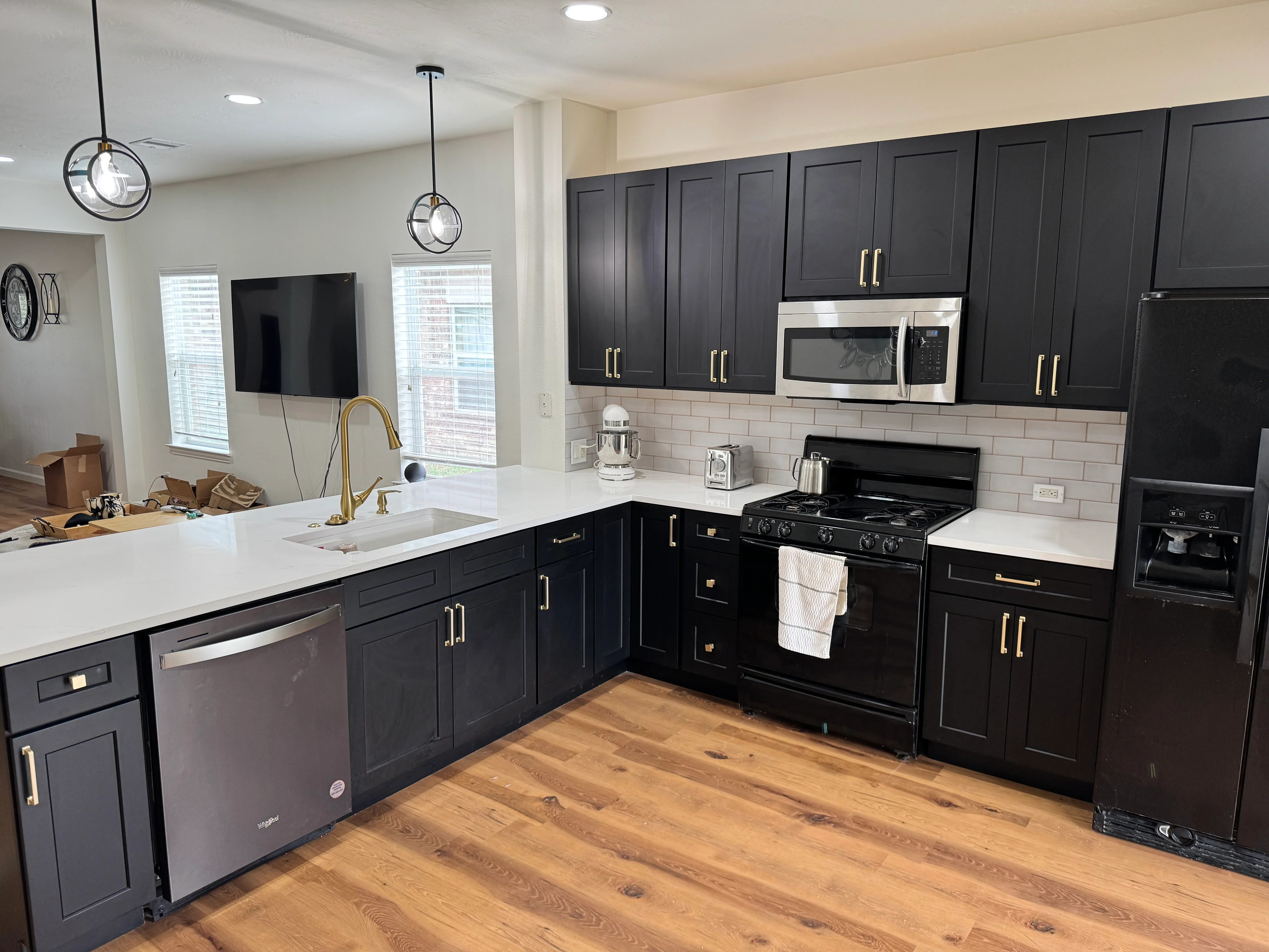 Modern kitchen with black cabinets, white counters, subway tile backsplash, and stainless steel appliances