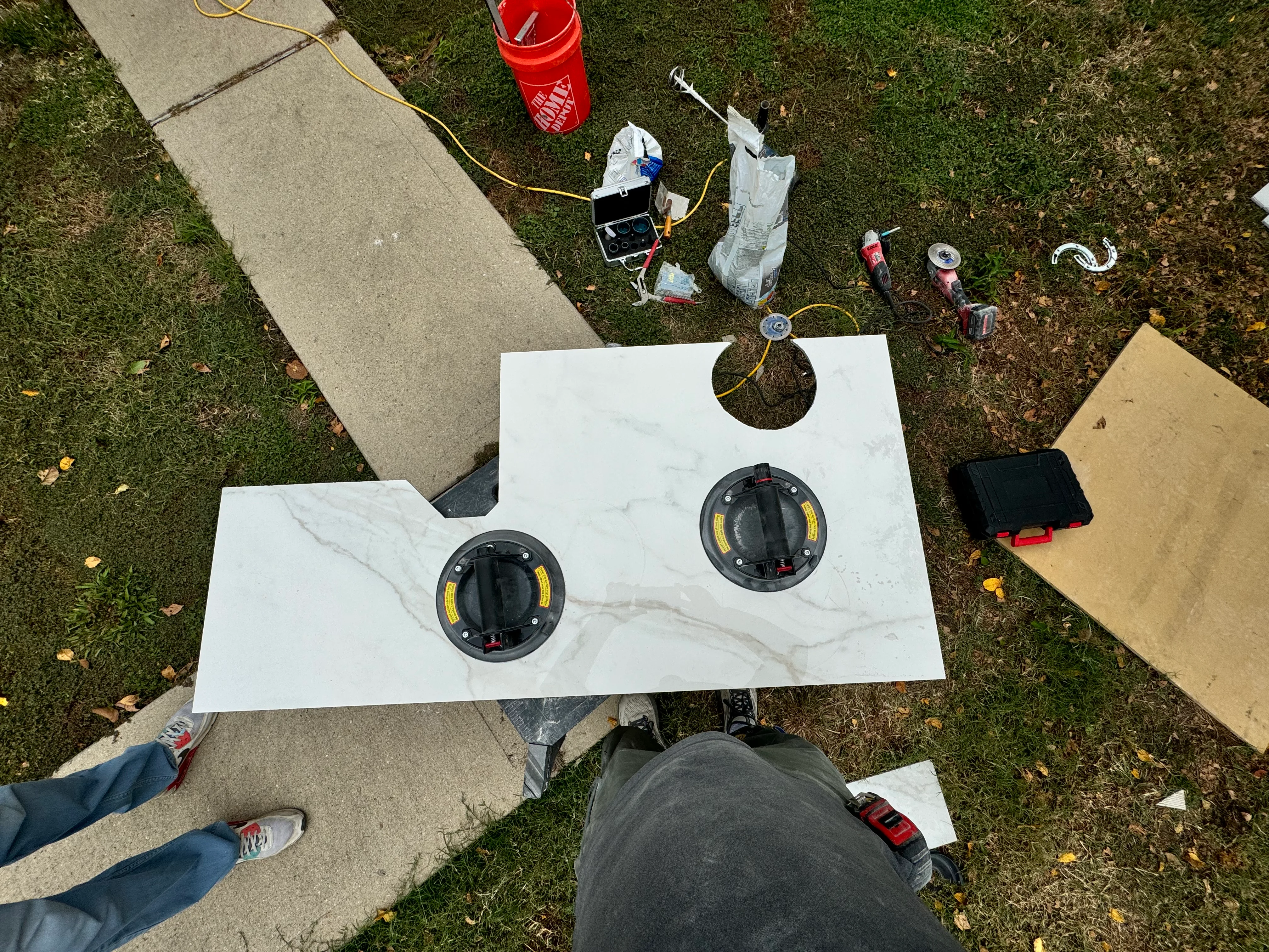 Two recessed electrical outlets with black trim rings installed in white marble-finish panel during electrical installation work