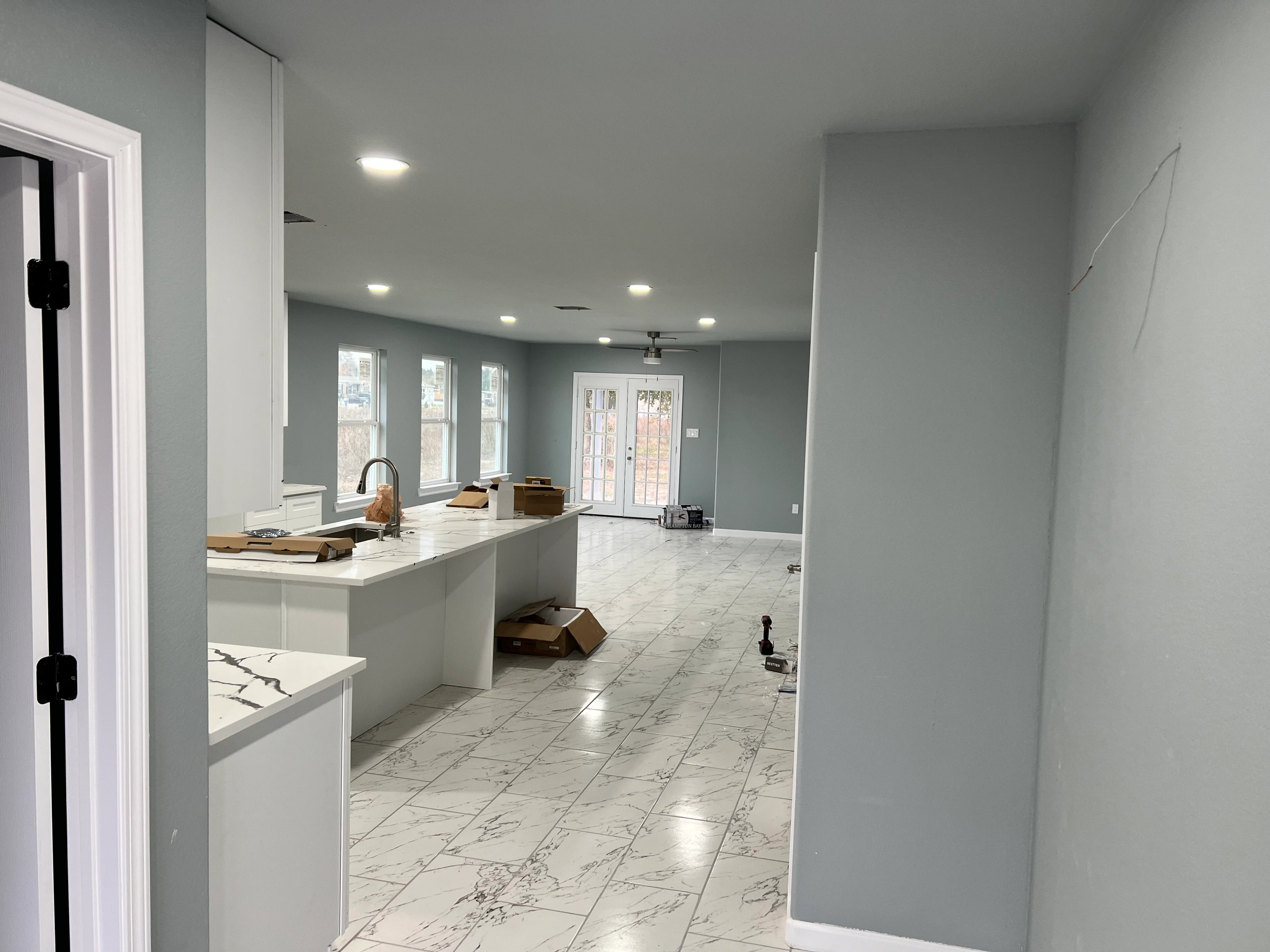 Modern kitchen with white cabinets, marble tile floor, and open living space