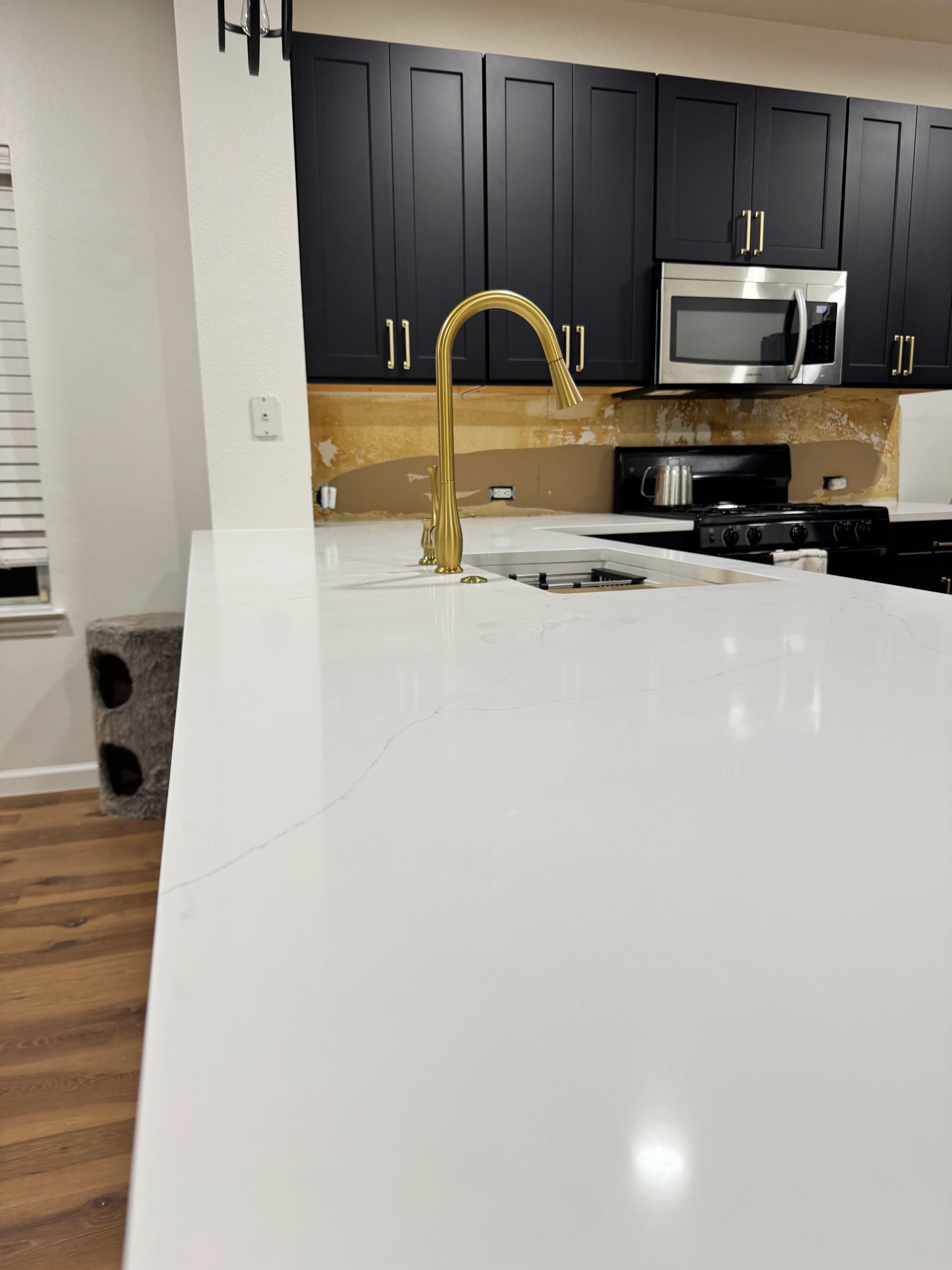 Modern kitchen with black cabinets, white quartz counters, and gold accents