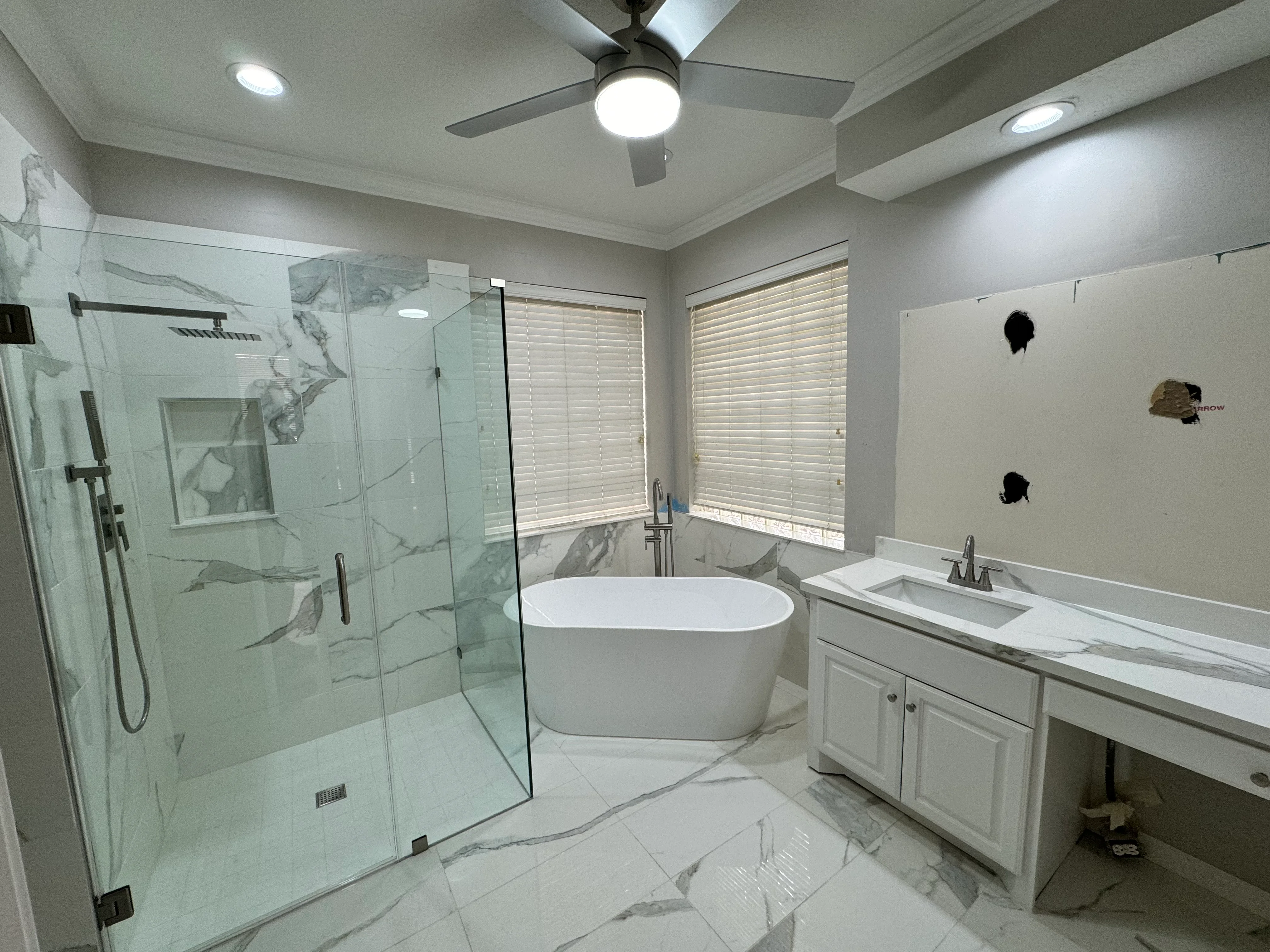Modern master bathroom with frameless shower, freestanding tub, and marble finishes