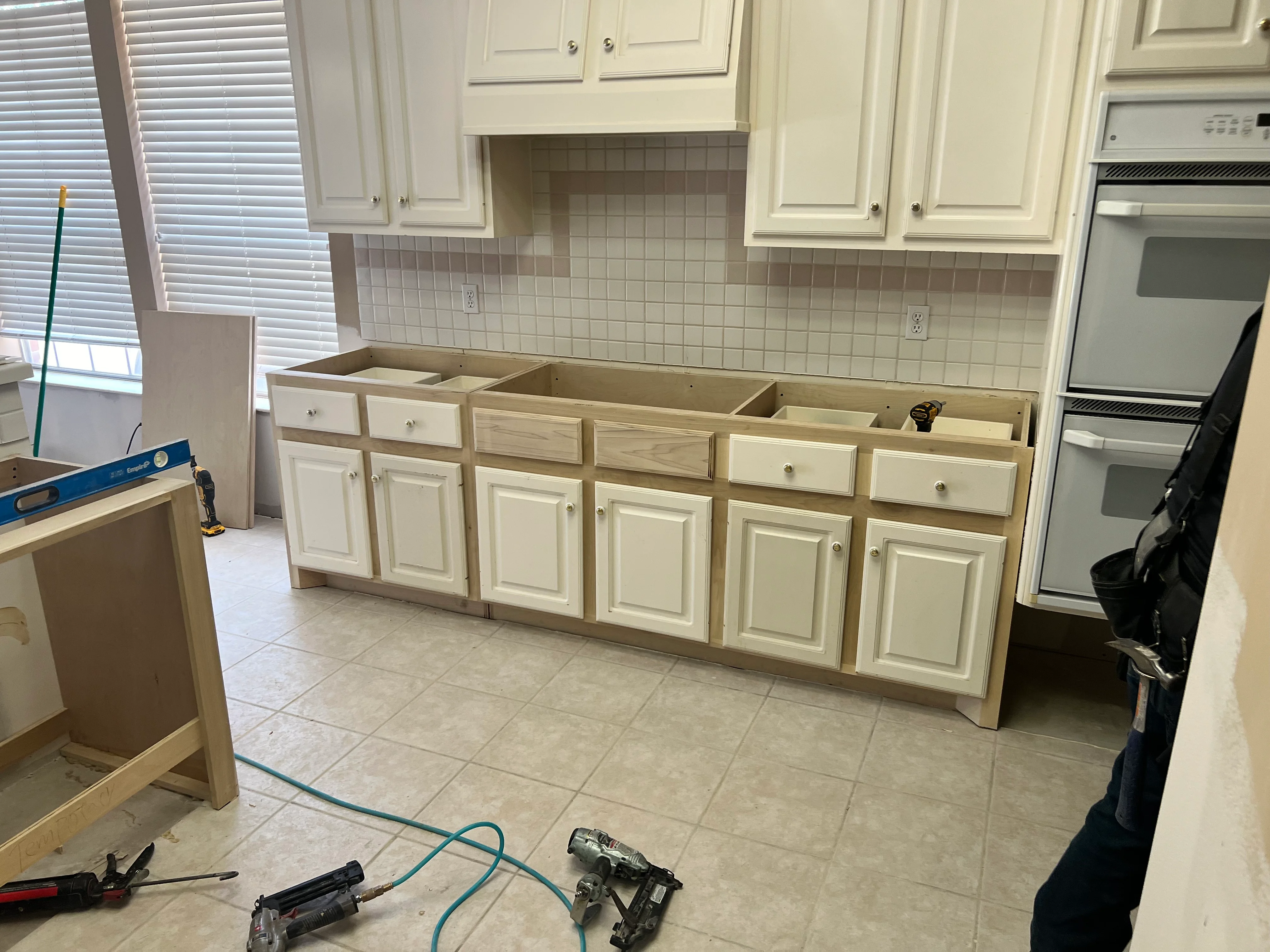 Kitchen remodel in progress showing cream cabinets and subway tile backsplash installation