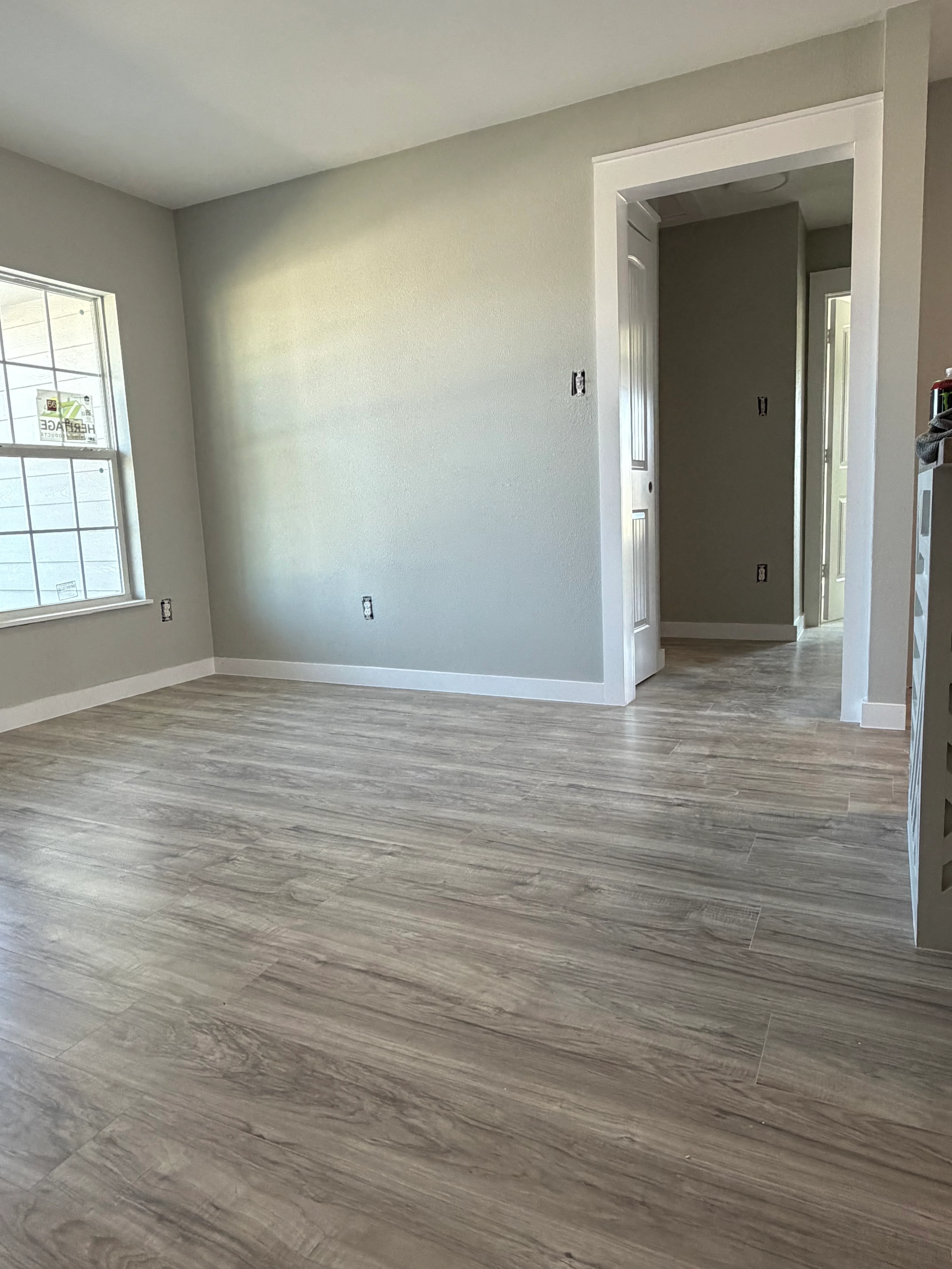 Newly remodeled bedroom with gray walls, white trim, and wood-look vinyl flooring