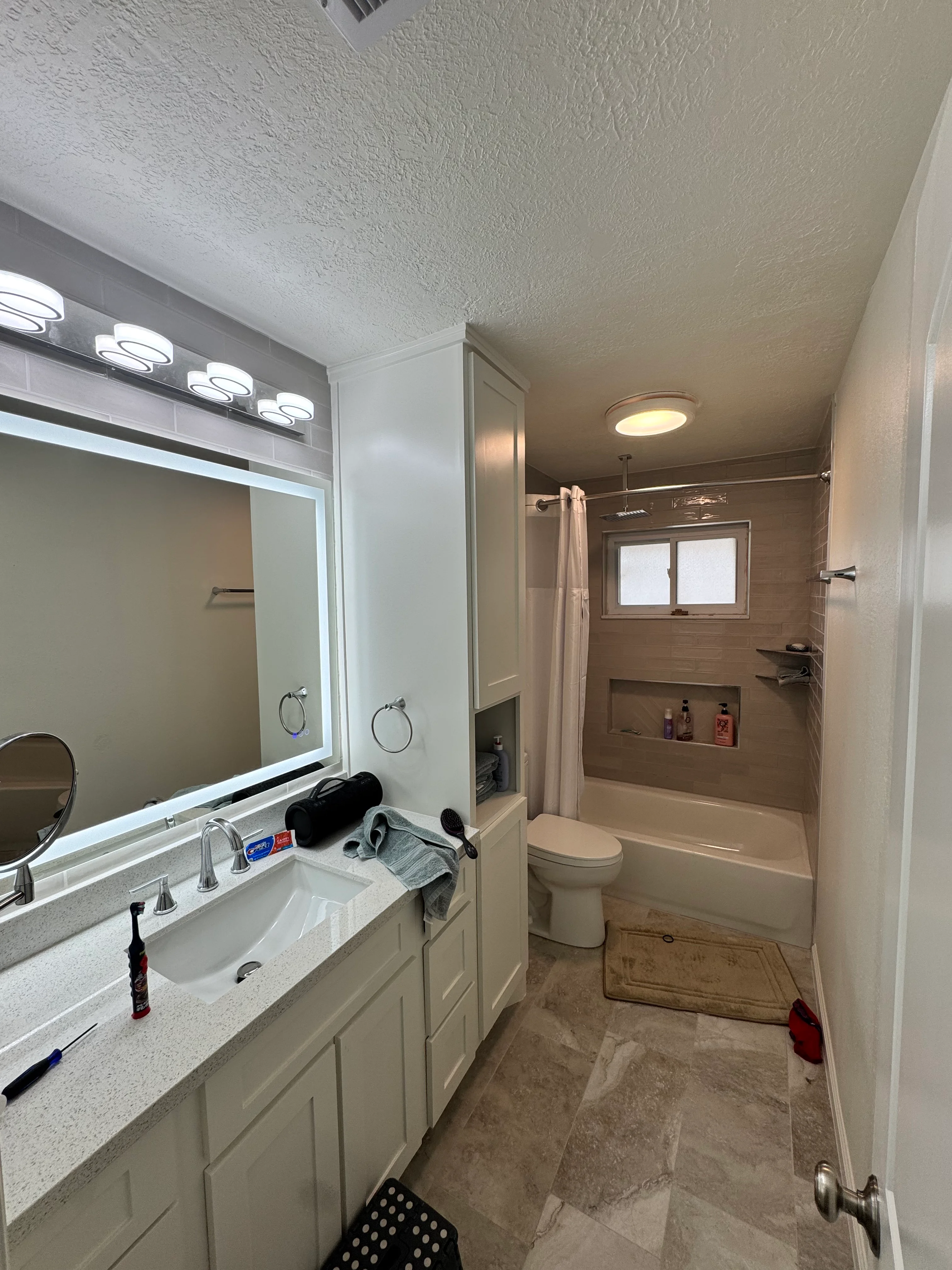 Modern bathroom with white vanity, lighted mirror, and wood-tile shower enclosure