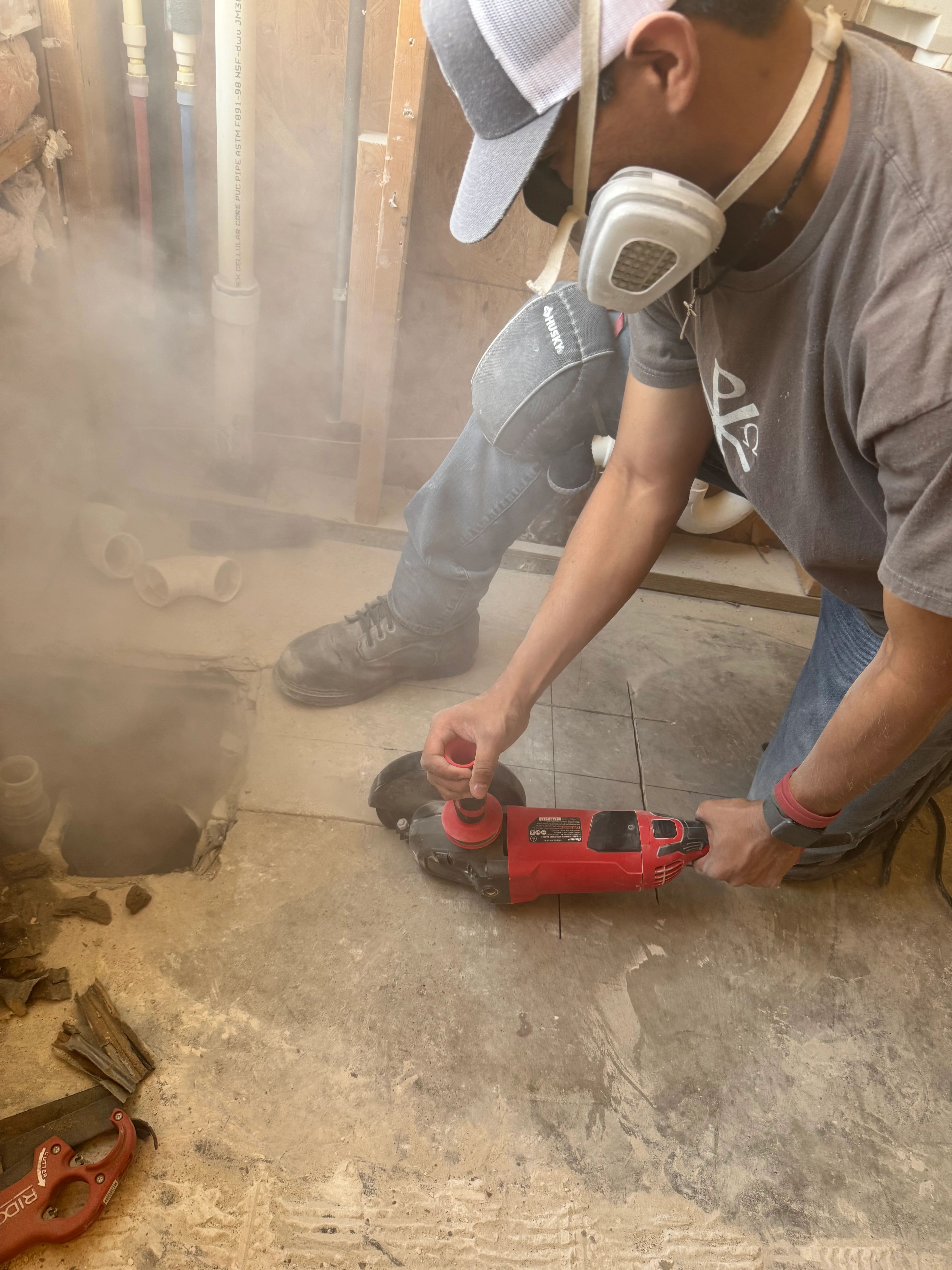 Worker using red concrete saw to cut concrete flooring during demolition phase