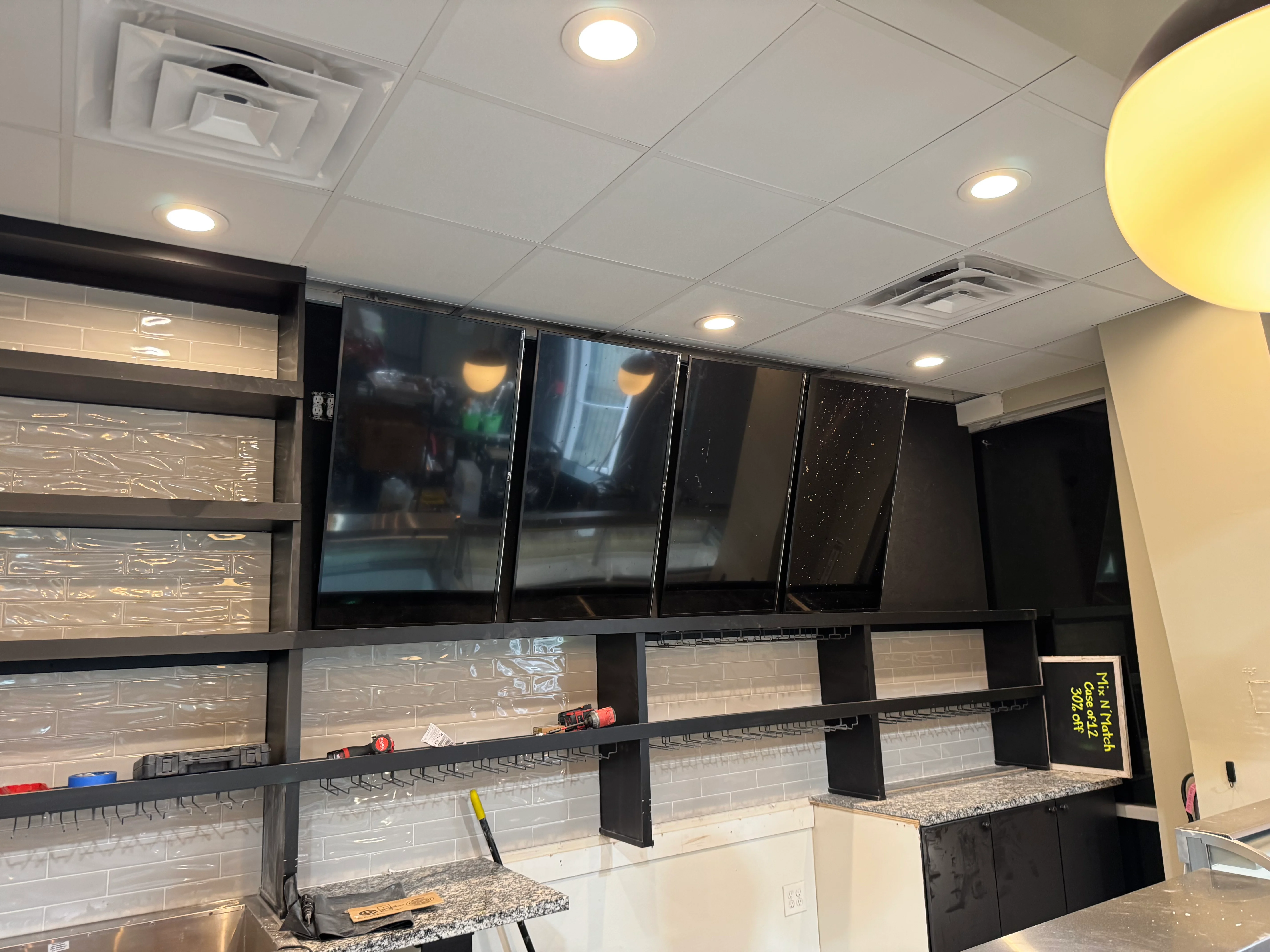 Modern commercial kitchen with black cabinetry, glass doors, white tile backsplash, and granite counters