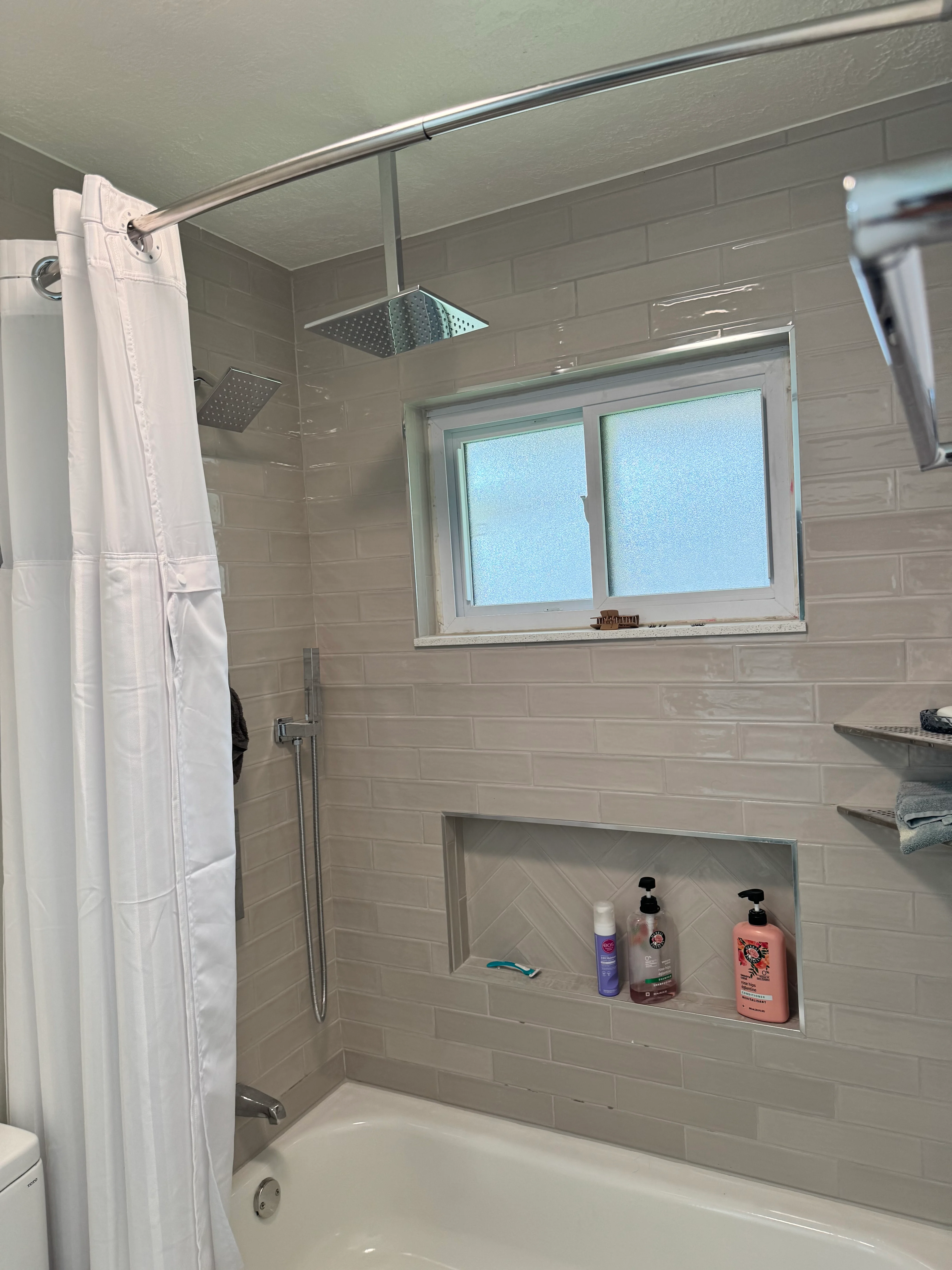 Modern bathroom shower with white subway tile, glass enclosure, and rainfall showerhead