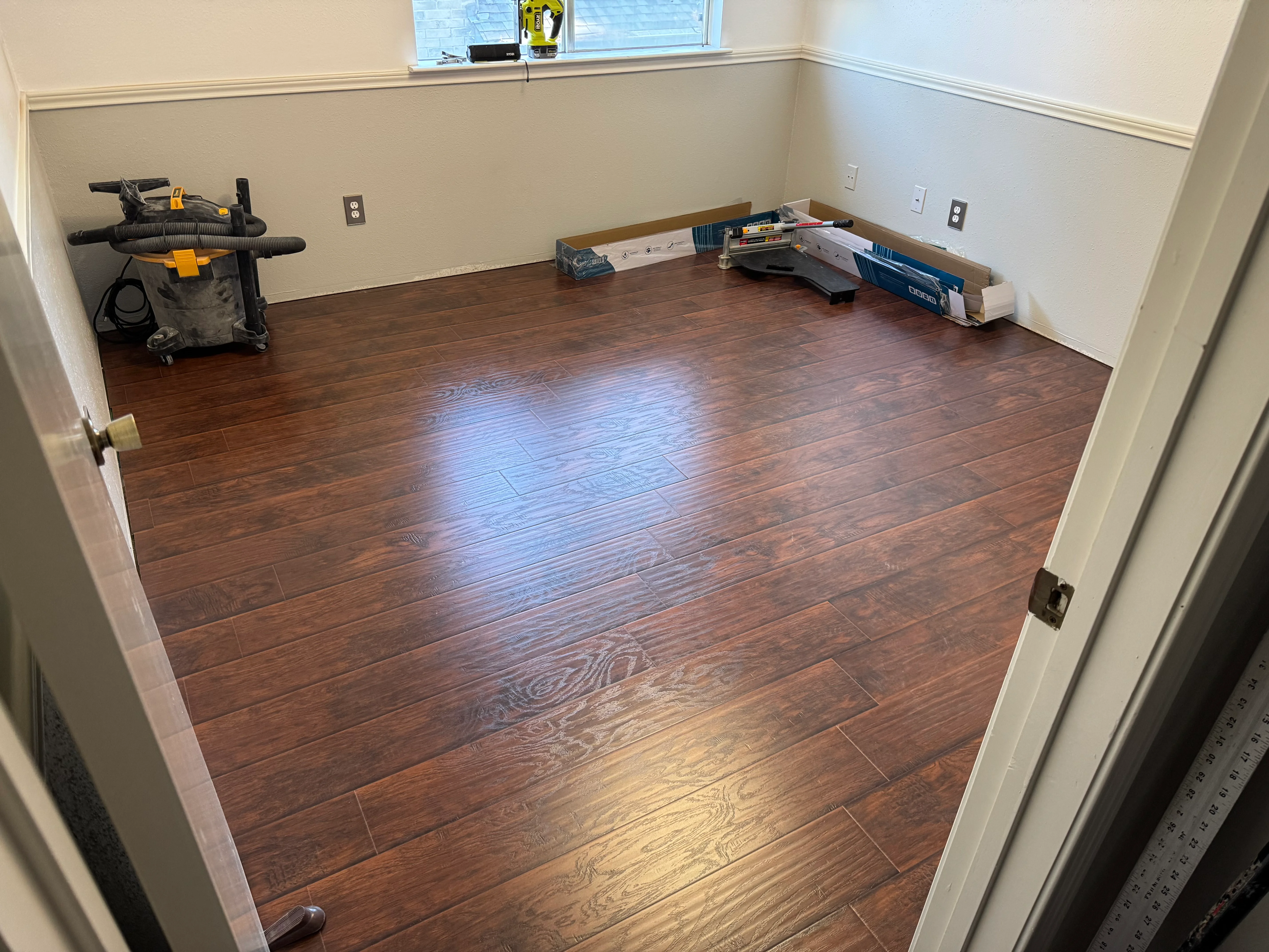Newly installed dark wood-tone laminate flooring in residential room with cream walls