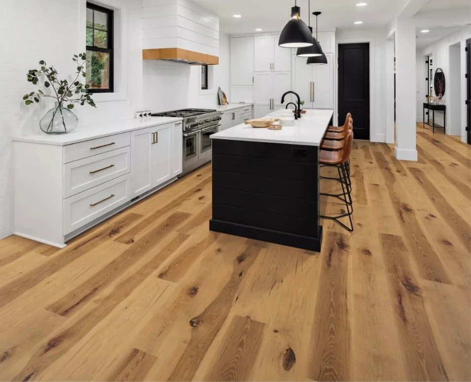 Modern kitchen with white cabinets, black island, hardwood floors, and pendant lights