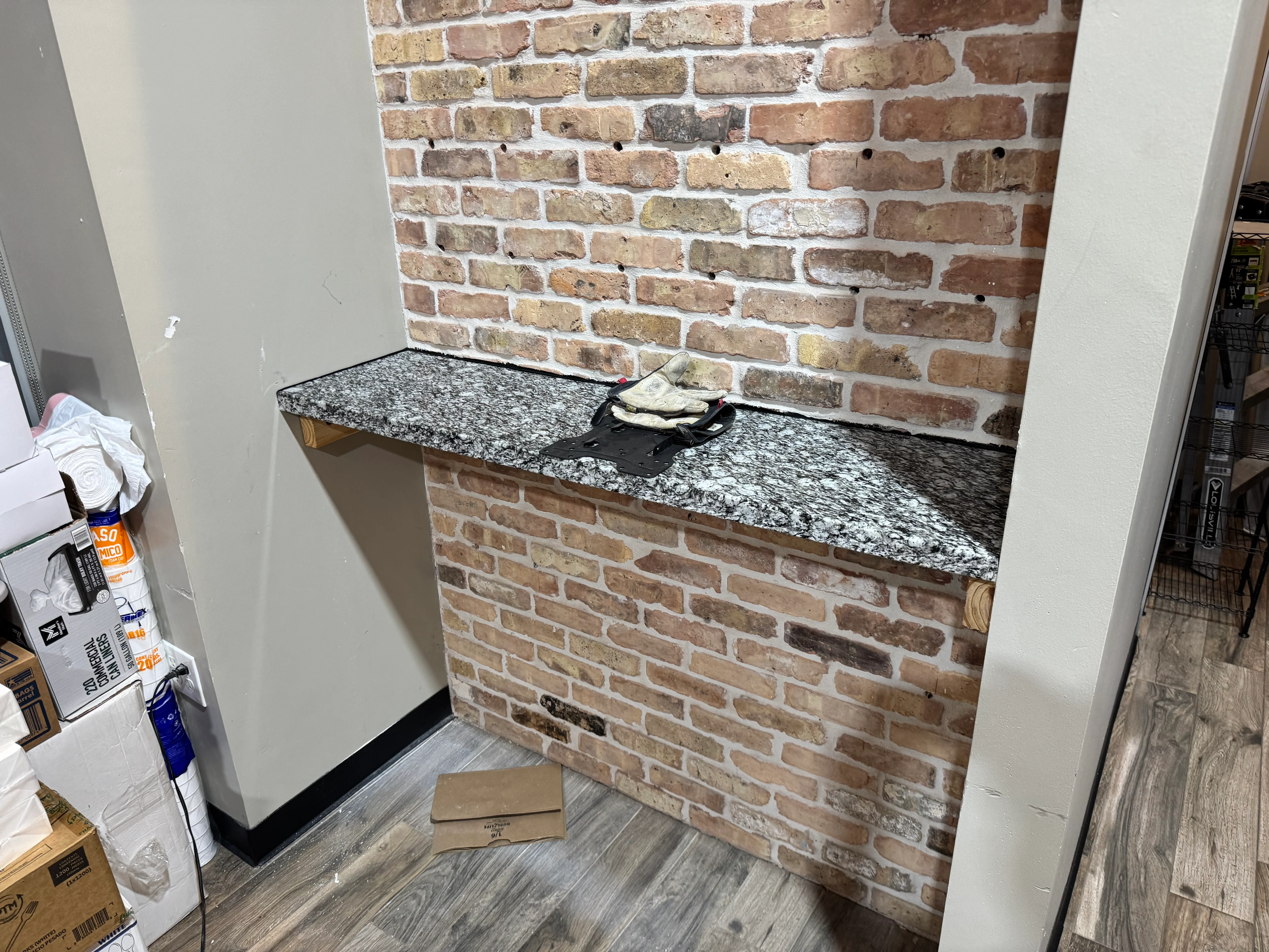 Exposed brick fireplace with white mortar and speckled granite countertop in residential interior
