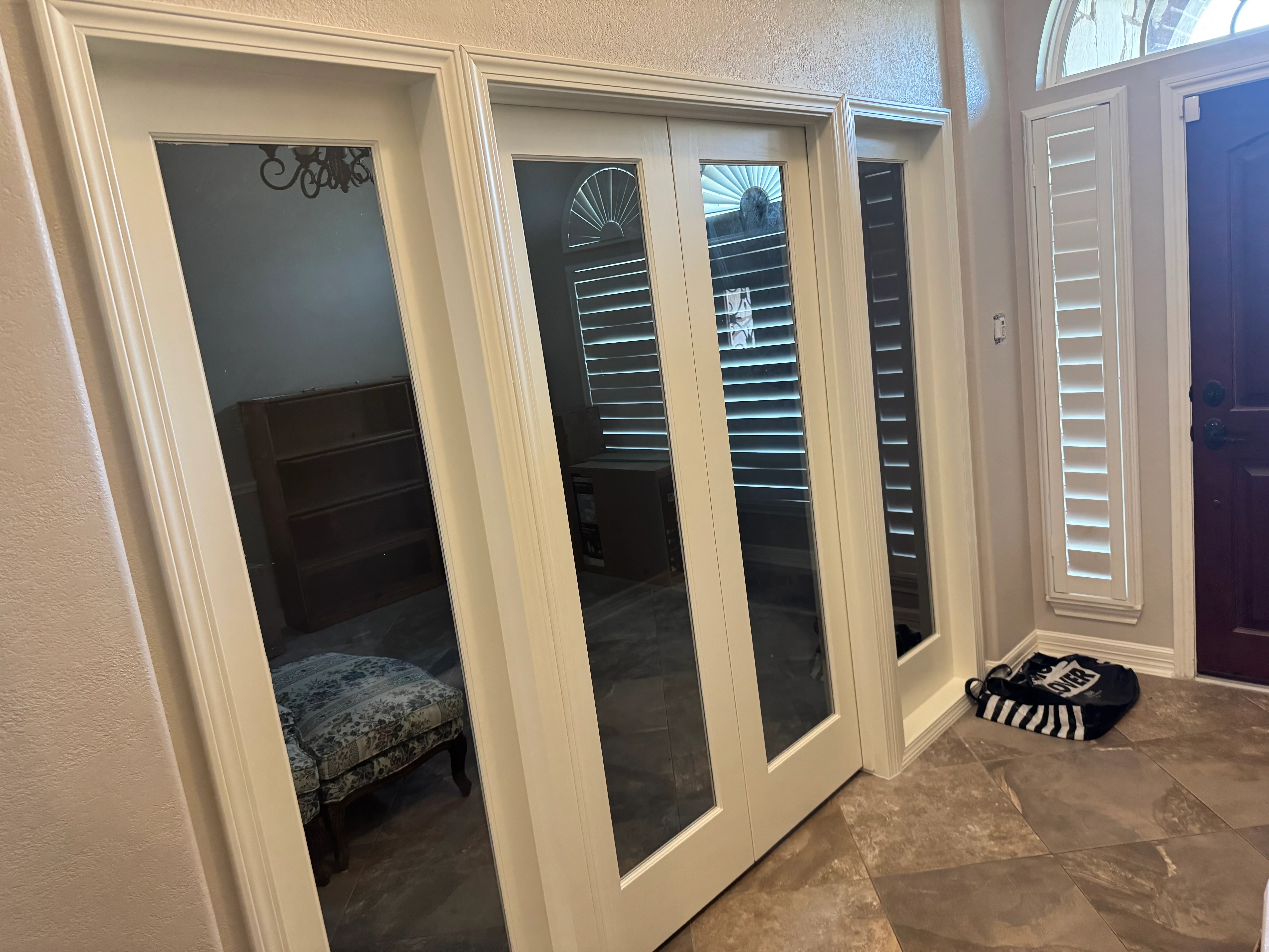 White-framed closet doors with black plantation shutters in master bedroom closet